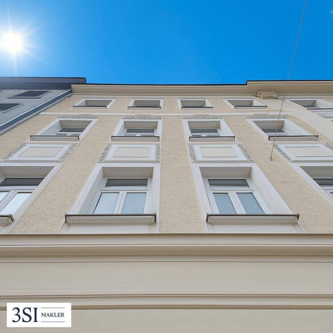 Fassade eines Gebäudes mit vielen Fenstern unter blauem Himmel und Sonnenschein.