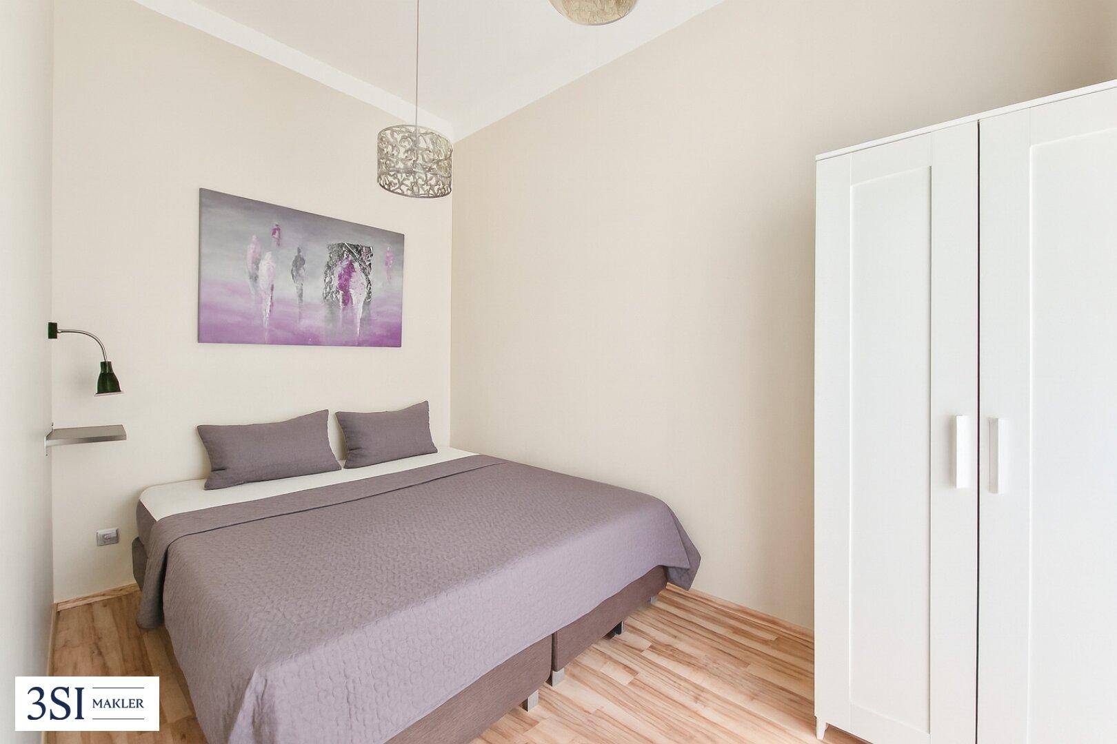 Gemütliches Schlafzimmer mit Doppelbett, weißem Kleiderschrank und Holzboden.