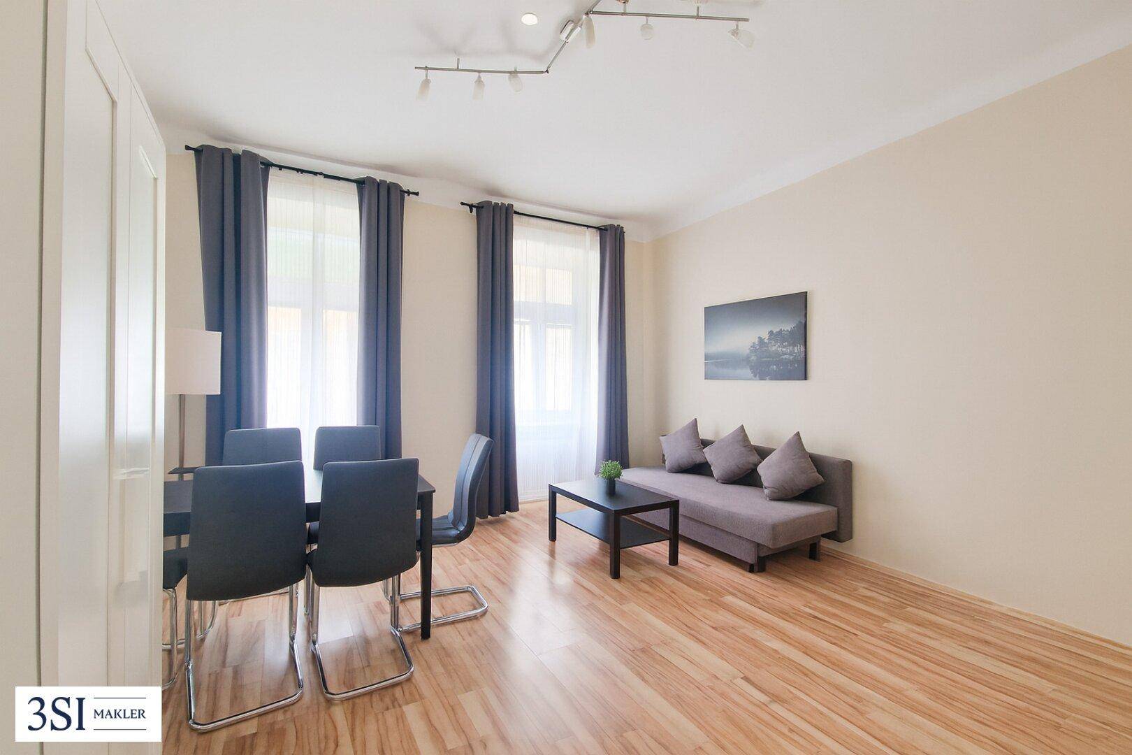 Heller Wohn- und Essbereich mit Holzboden, Sofa und Esstisch für mehrere Personen.