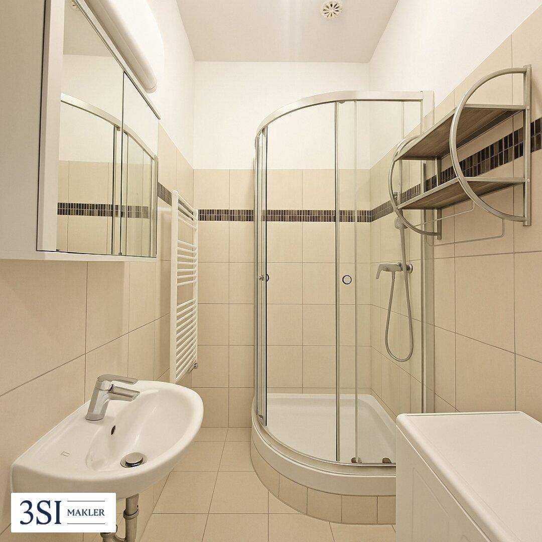 Kleines Badezimmer mit Duschkabine, Waschbecken und Fliesen in Beige- und Brauntönen, inklusive Spiegelschrank.