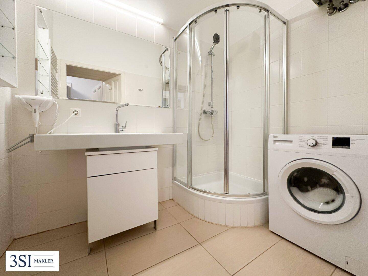 Modernes Badezimmer mit Duschkabine, Waschbecken, großem Spiegel und Waschmaschine.