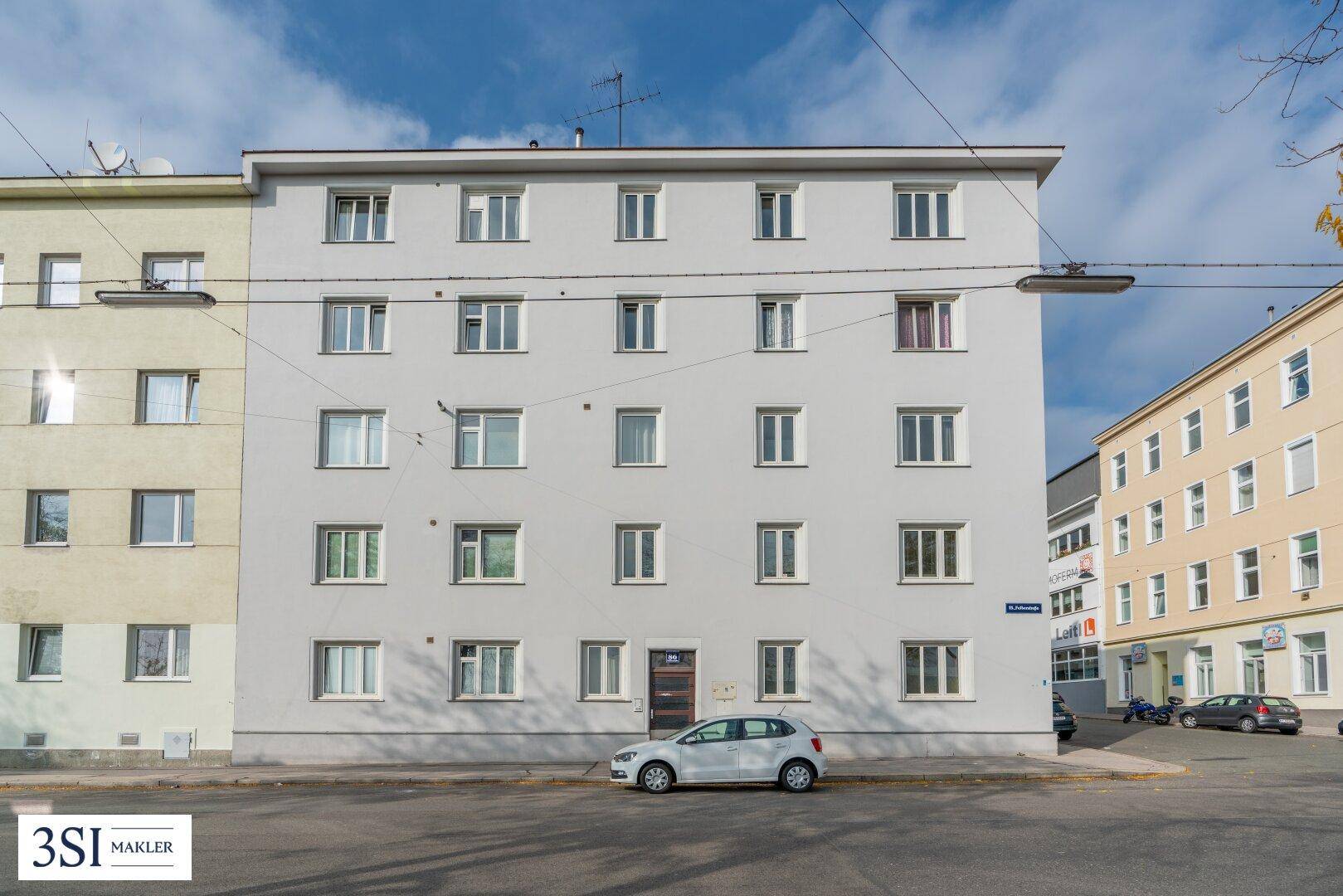 Mehrstöckiges Wohngebäude mit schlichter Fassade und vielen Fenstern an einer ruhigen Straße.