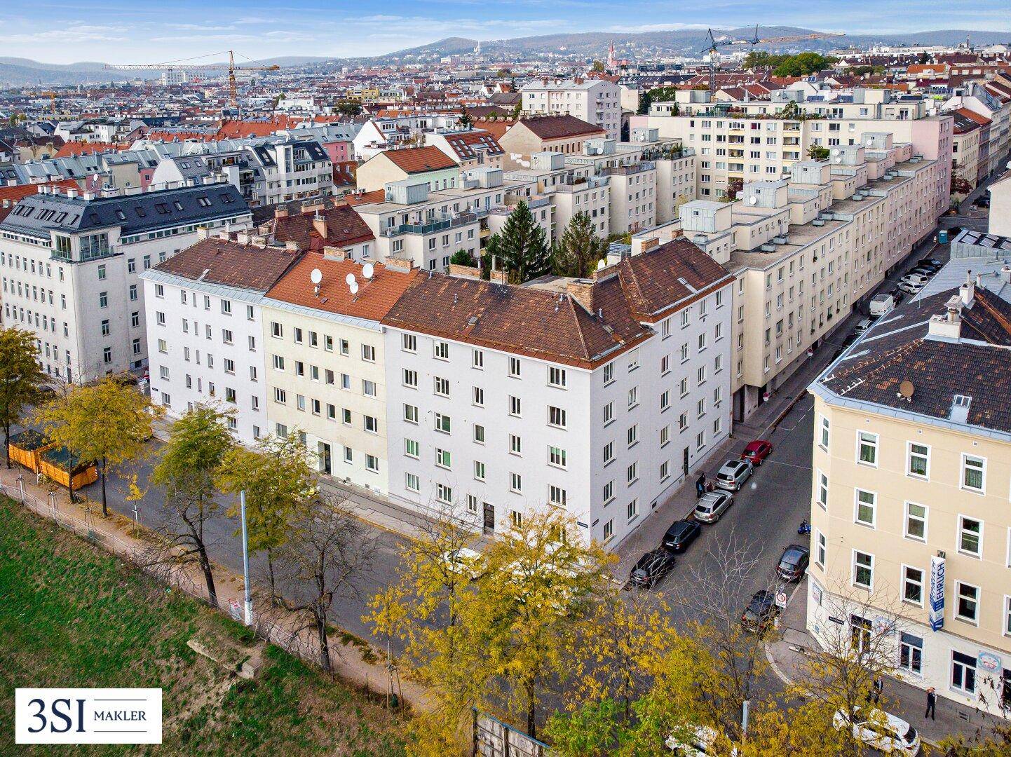 Luftaufnahme eines Wohnviertels mit Gebäuden, Straßen und Bäumen in einer städtischen Umgebung.