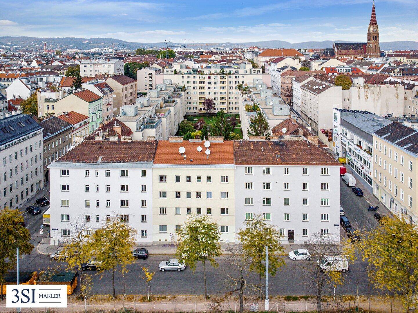 Weitläufige Luftaufnahme eines Wohngebiets mit Gebäuden, Dächern und grünen Innenhöfen.