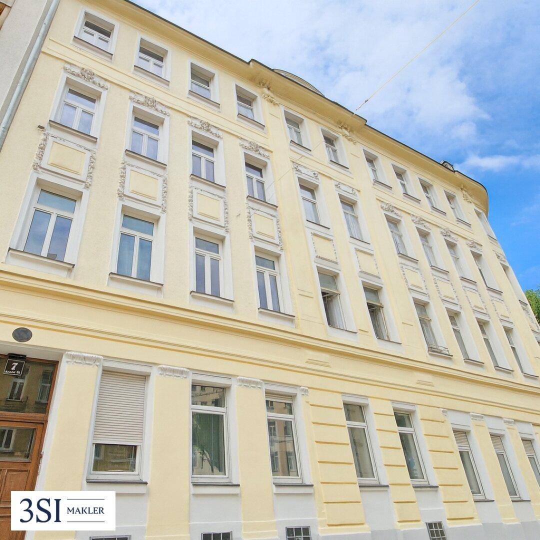 Die renovierte Fassade eines Mehrfamilienhauses mit vielen Fenstern und Rollläden.