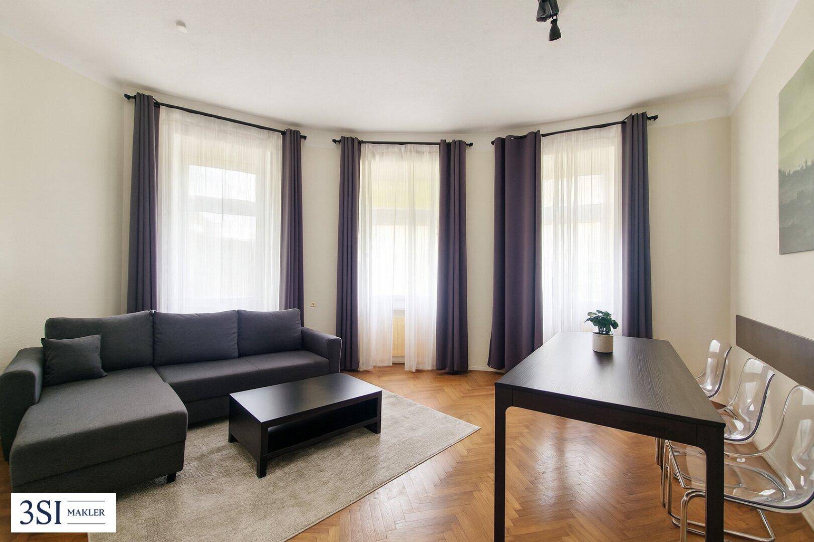 Geräumiger Wohn-Essbereich mit Fischgrätparkett, bequemer Couch und Esstisch.