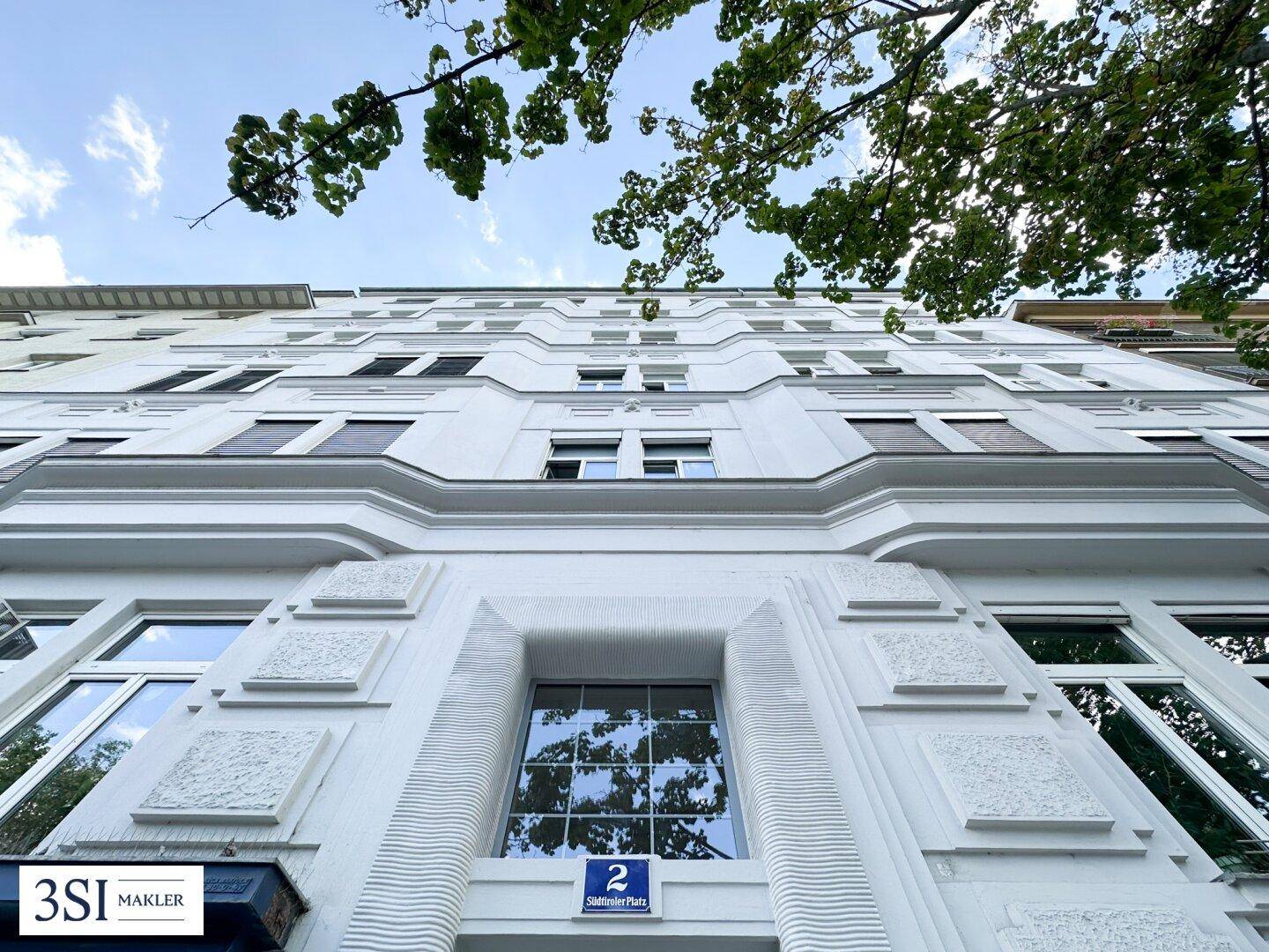 Klassische Fassade eines Altbaus mit vielen Fenstern und dekorativen Elementen.