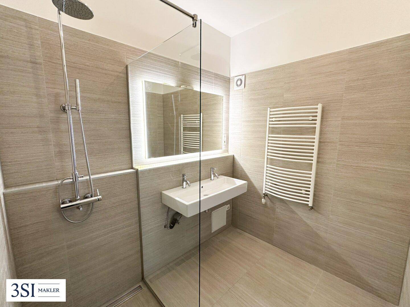 Modernes Badezimmer mit begehbarer Dusche, Doppelwaschbecken und beheiztem Handtuchhalter.