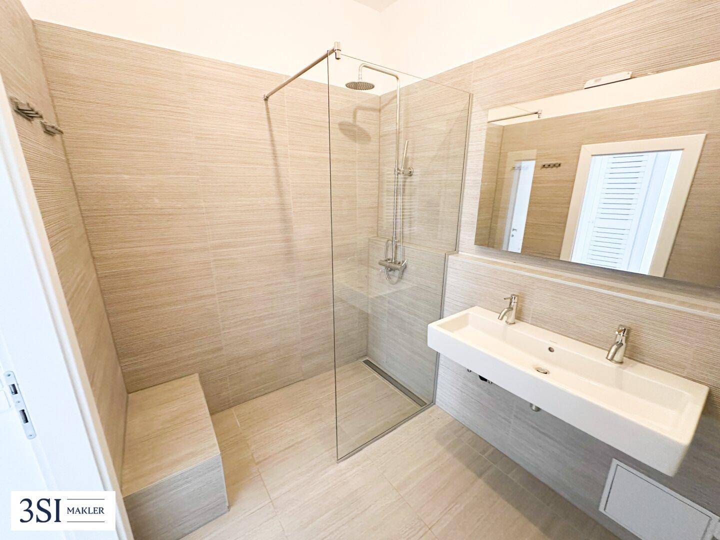 Geräumiges, modernes Badezimmer mit großer begehbarer Dusche und Doppelwaschbecken.