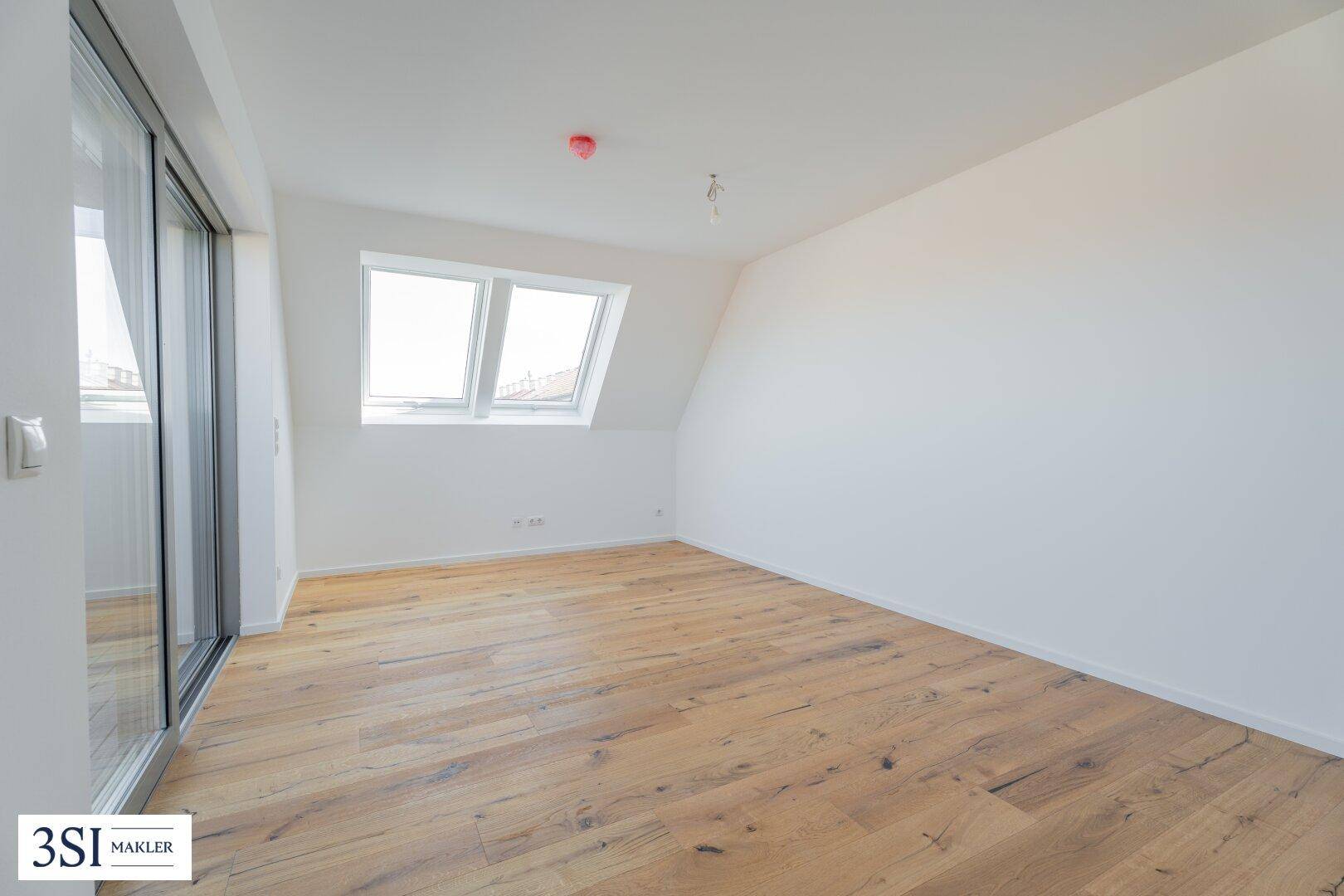 Helles Zimmer mit Holzboden, Dachfenstern und Schiebetür zur Terrasse, ideal für Wohnzwecke.
