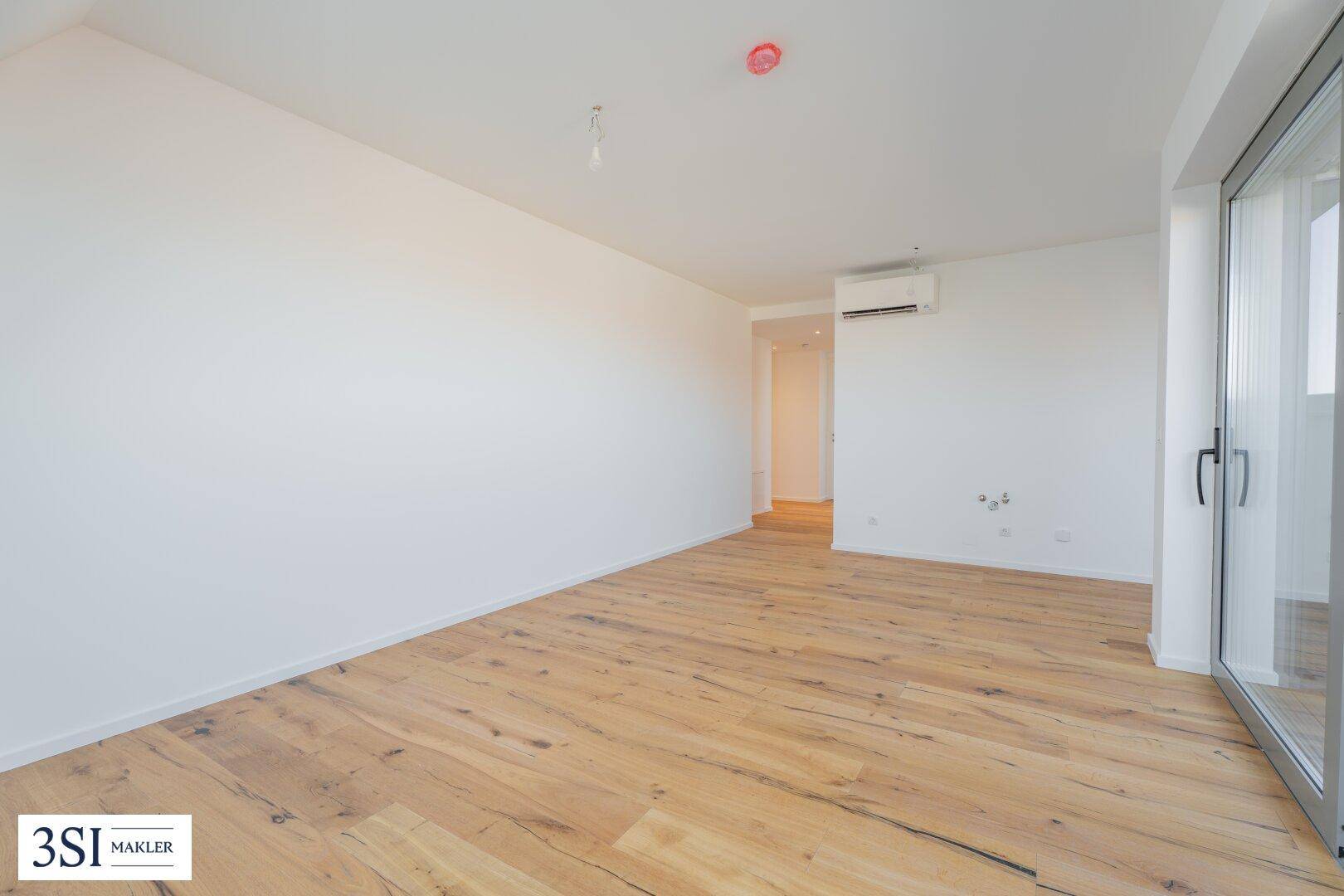 Geräumiges, helles Zimmer mit Holzboden und Zugang zu einem Außenbereich, ideal für Wohnzwecke.