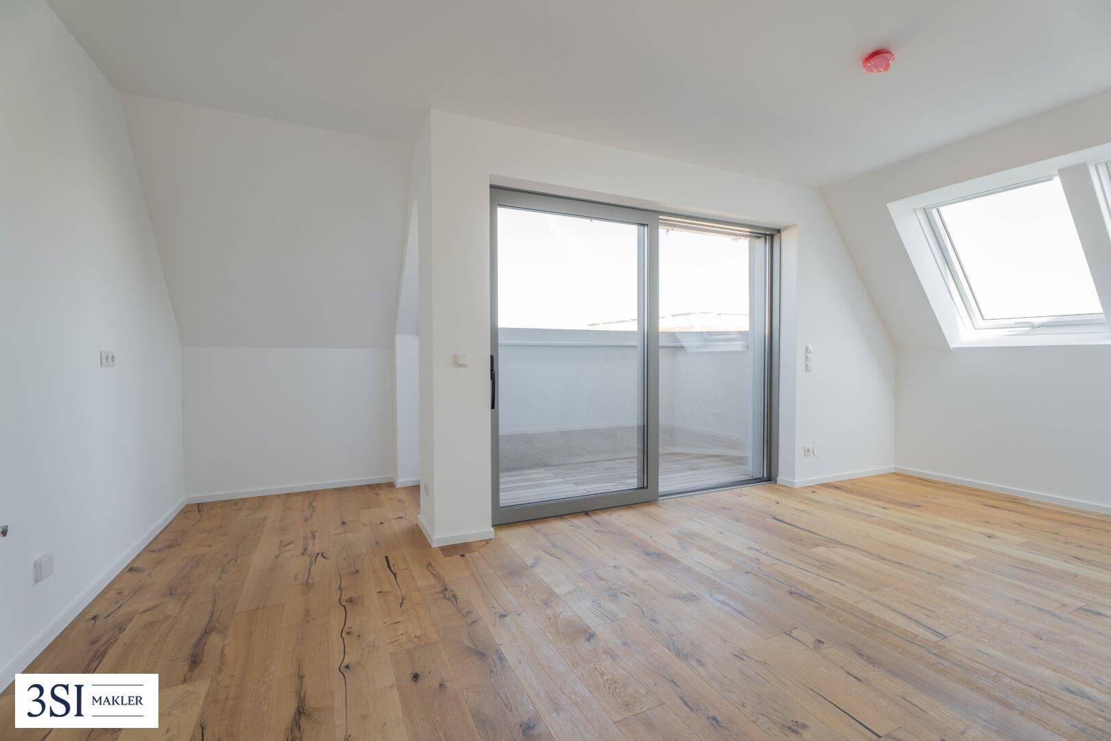 Geräumiges Zimmer mit Holzboden, Dachfenstern und großem Terrassenzugang, bietet viel Licht.