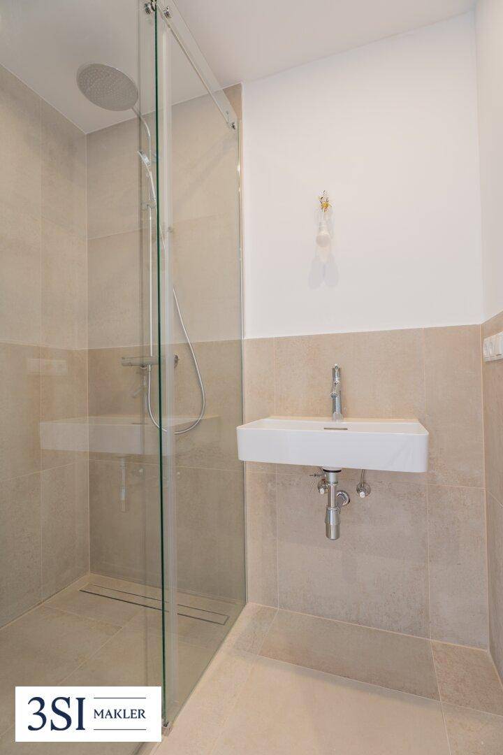 Modernes Badezimmer mit begehbarer Dusche, Regendusche und beigefarbenen Fliesen.