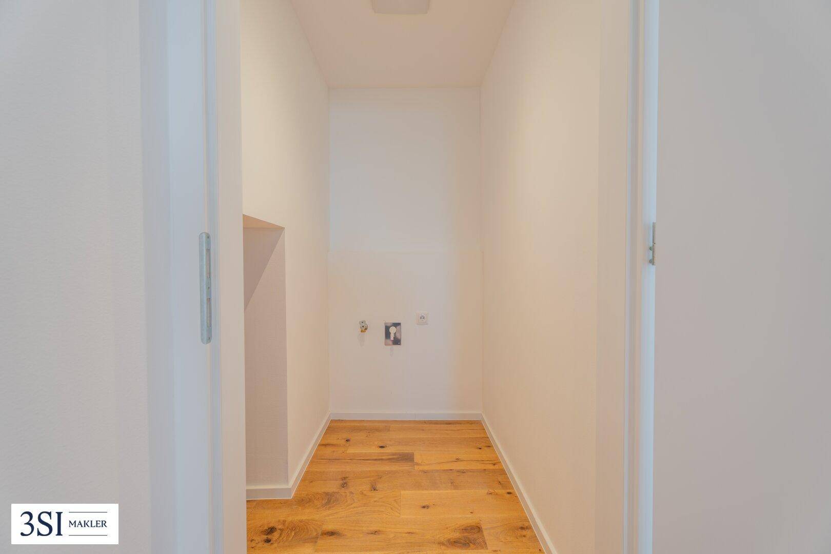 Praktischer Hauswirtschaftsraum mit Anschlüssen für Waschmaschine und Trockner, Holzboden.
