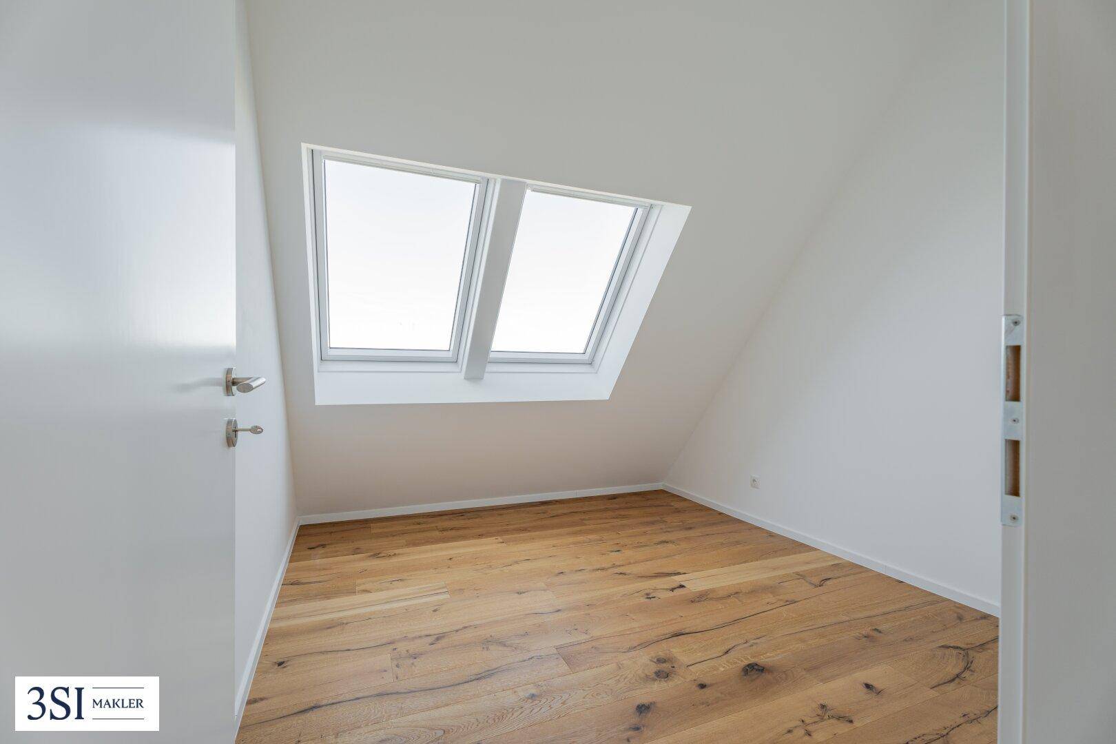 Kleinerer Raum mit Holzboden und zwei hellen Dachfenstern, ideal als Schlaf- oder Arbeitszimmer.