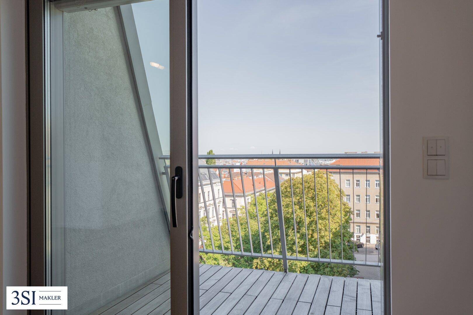 Kleiner Balkon mit Metallgeländer und Blick auf die umliegenden Stadtgebäude und Bäume.