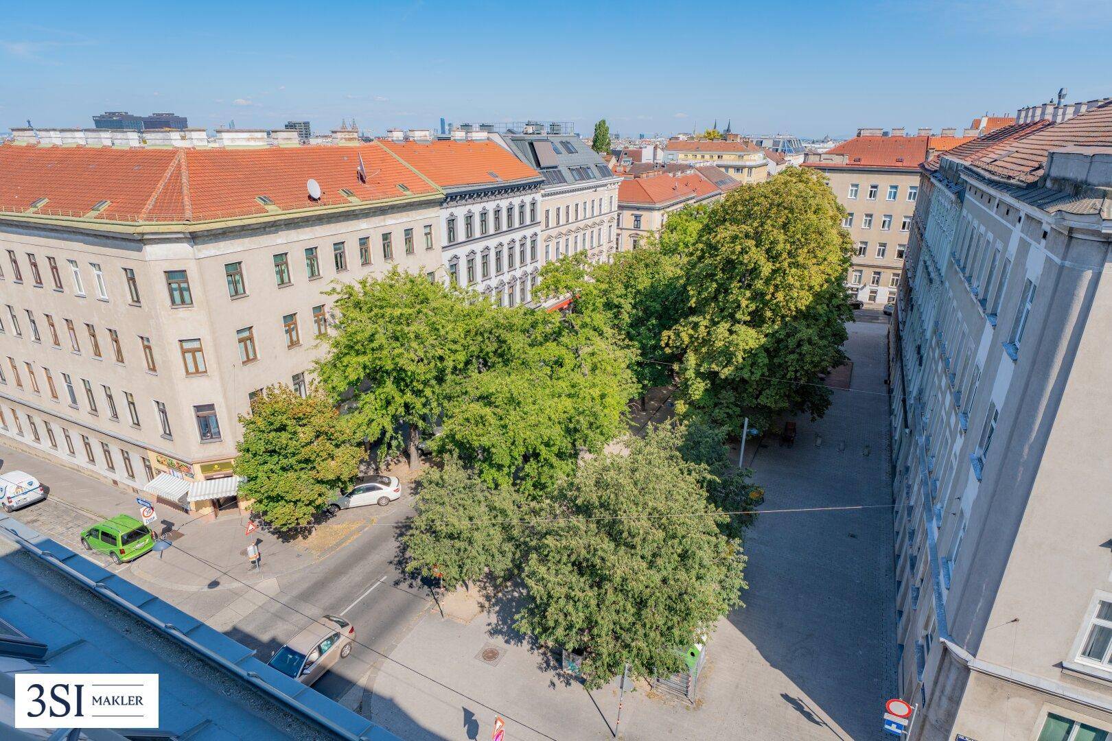 Panoramablick über eine belebte Stadtstraße mit historischen Gebäuden und grünen Bäumen.
