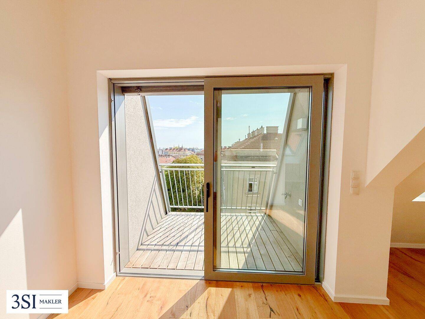 Sonniger Balkon mit Holzboden und weitem Blick über die Dächer der Stadt.