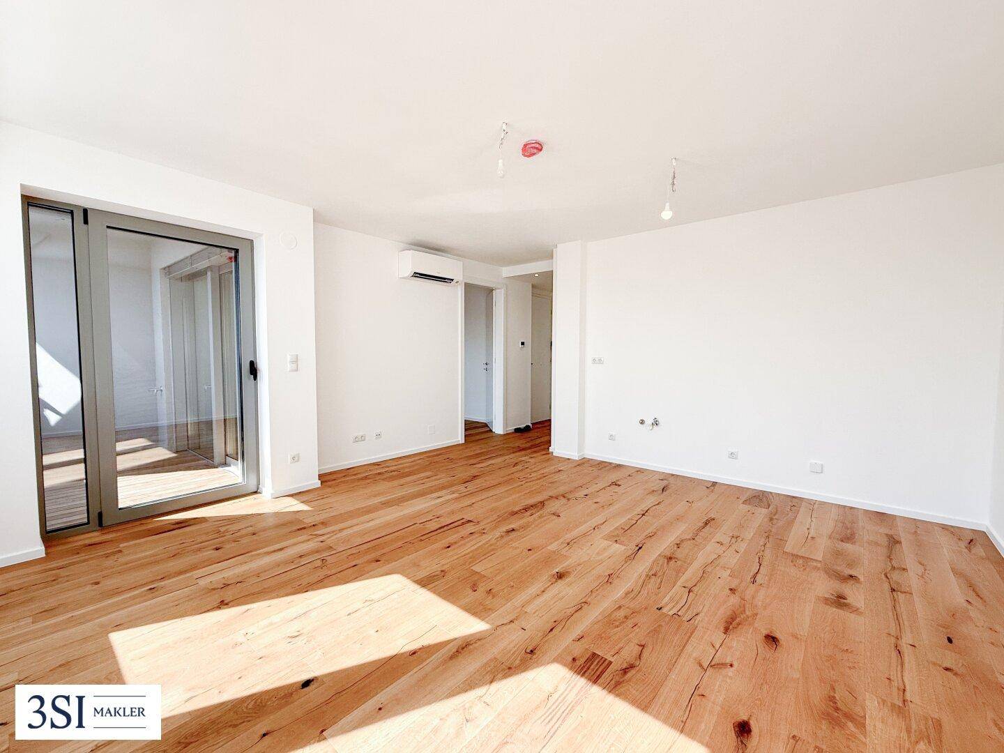 Geräumiges Zimmer mit Holzboden, Klimaanlage und Zugang zu einem Außenbereich, ideal für flexible Nutzung.