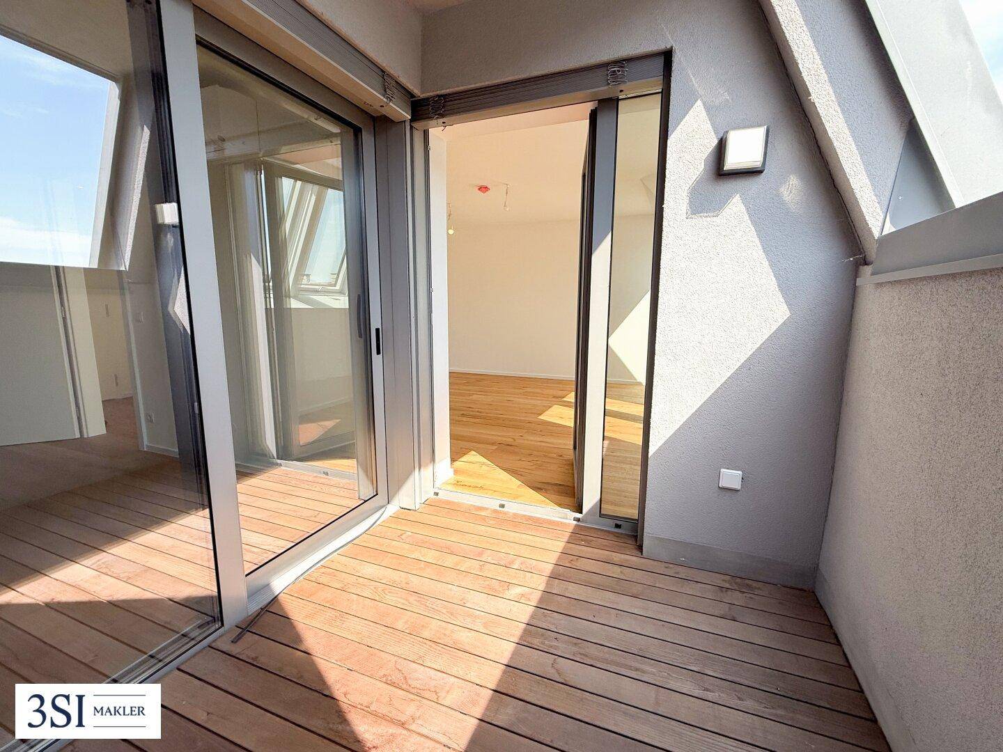 Heller Balkon mit Holzdielenboden und Glasschiebetür, bietet einen angenehmen Außenbereich.