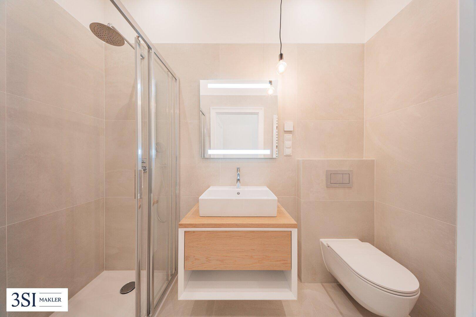 Modernes Badezimmer mit begehbarer Dusche, Einzelwaschbecken und wandhängendem WC in hellen Beigetönen.