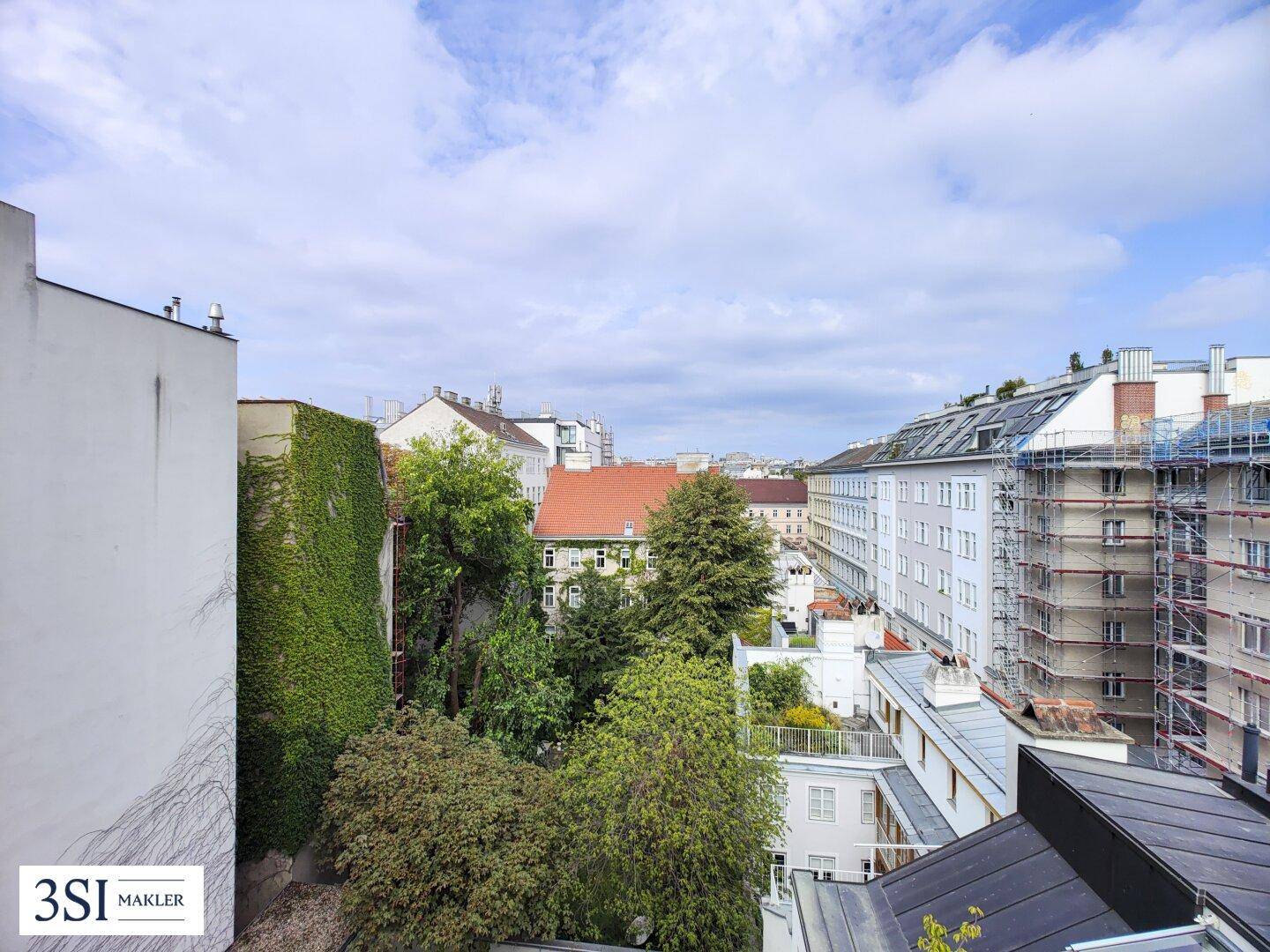 Blick über die Dächer der Stadt mit umliegenden Gebäuden und viel Grün.
