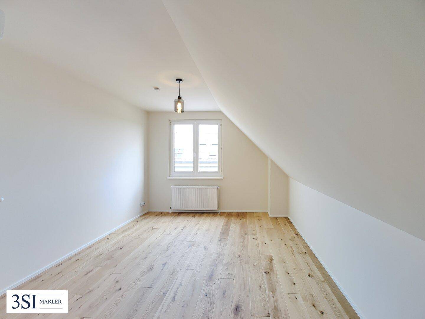 Geräumiges Schlafzimmer mit Parkettboden, Dachschräge und viel Tageslicht.