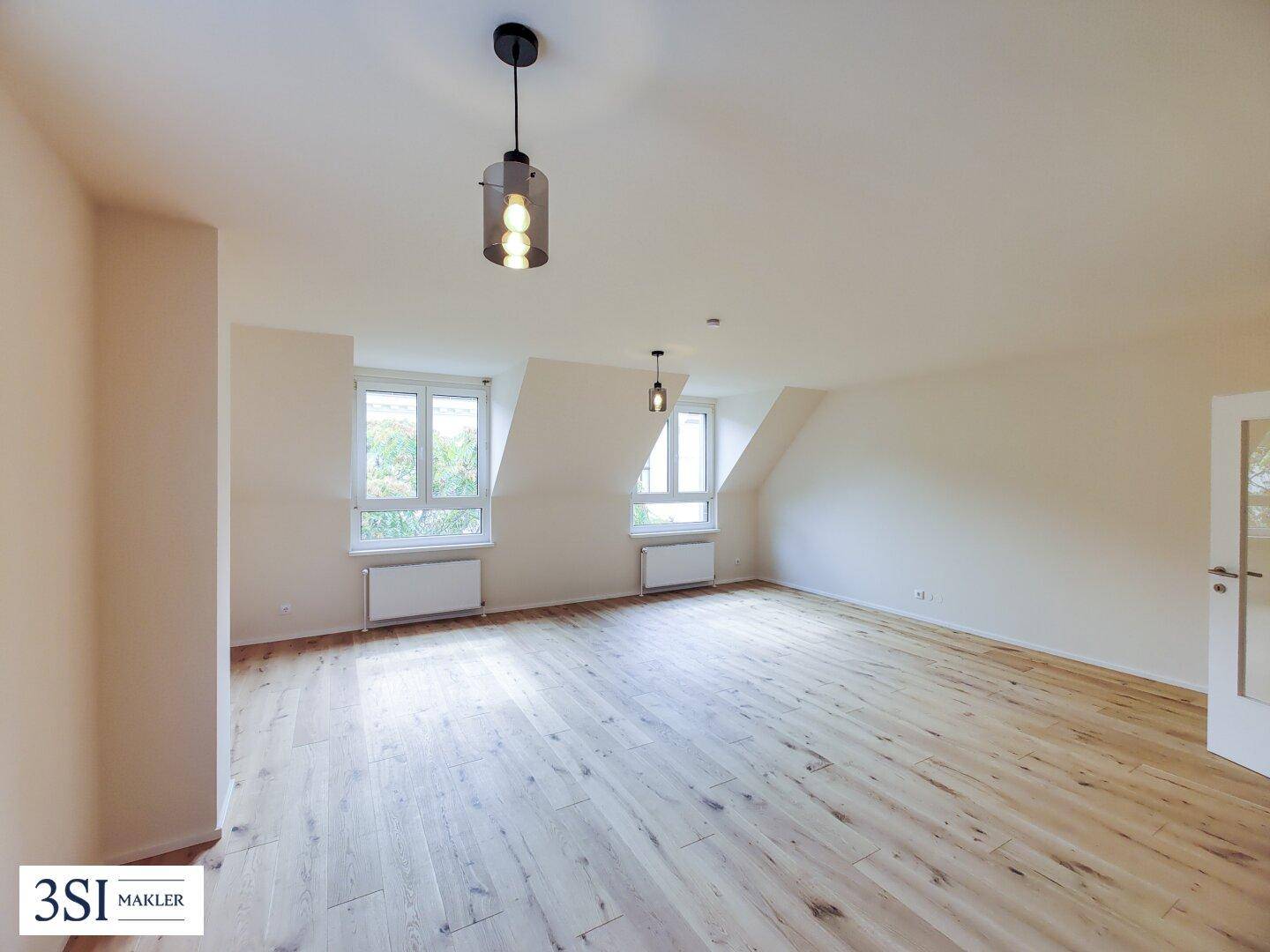 Großer Wohnraum mit Parkettboden, Dachschrägen und viel Tageslicht.
