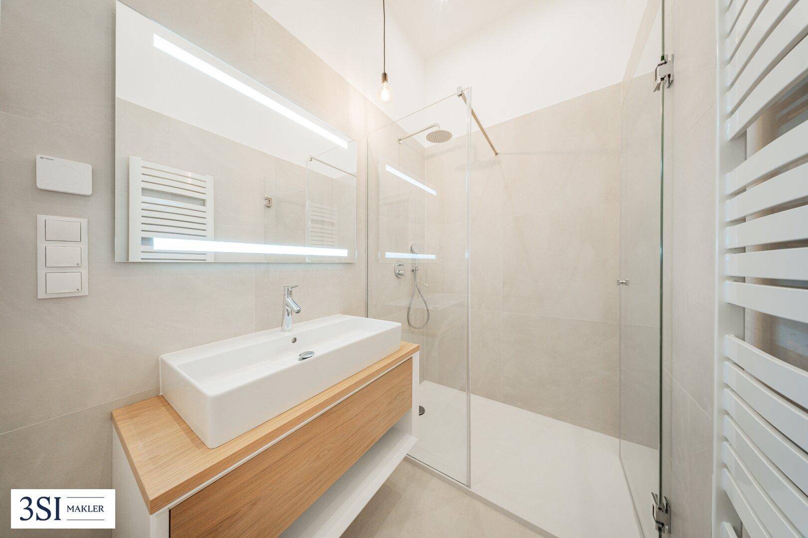 Modernes Badezimmer mit großem Spiegel, begehbarer Dusche und stilvollem Waschtisch mit Holzunterschrank.