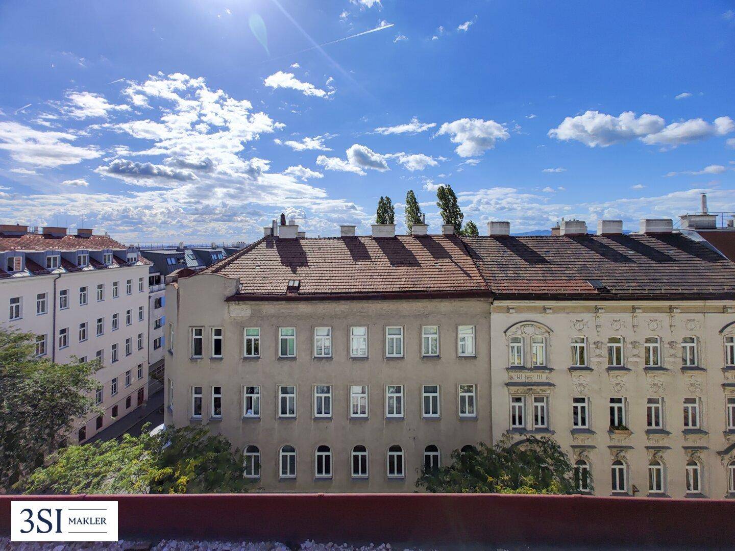 Weitblick über die Dächer der Stadt mit blauem Himmel und einigen Wolken.
