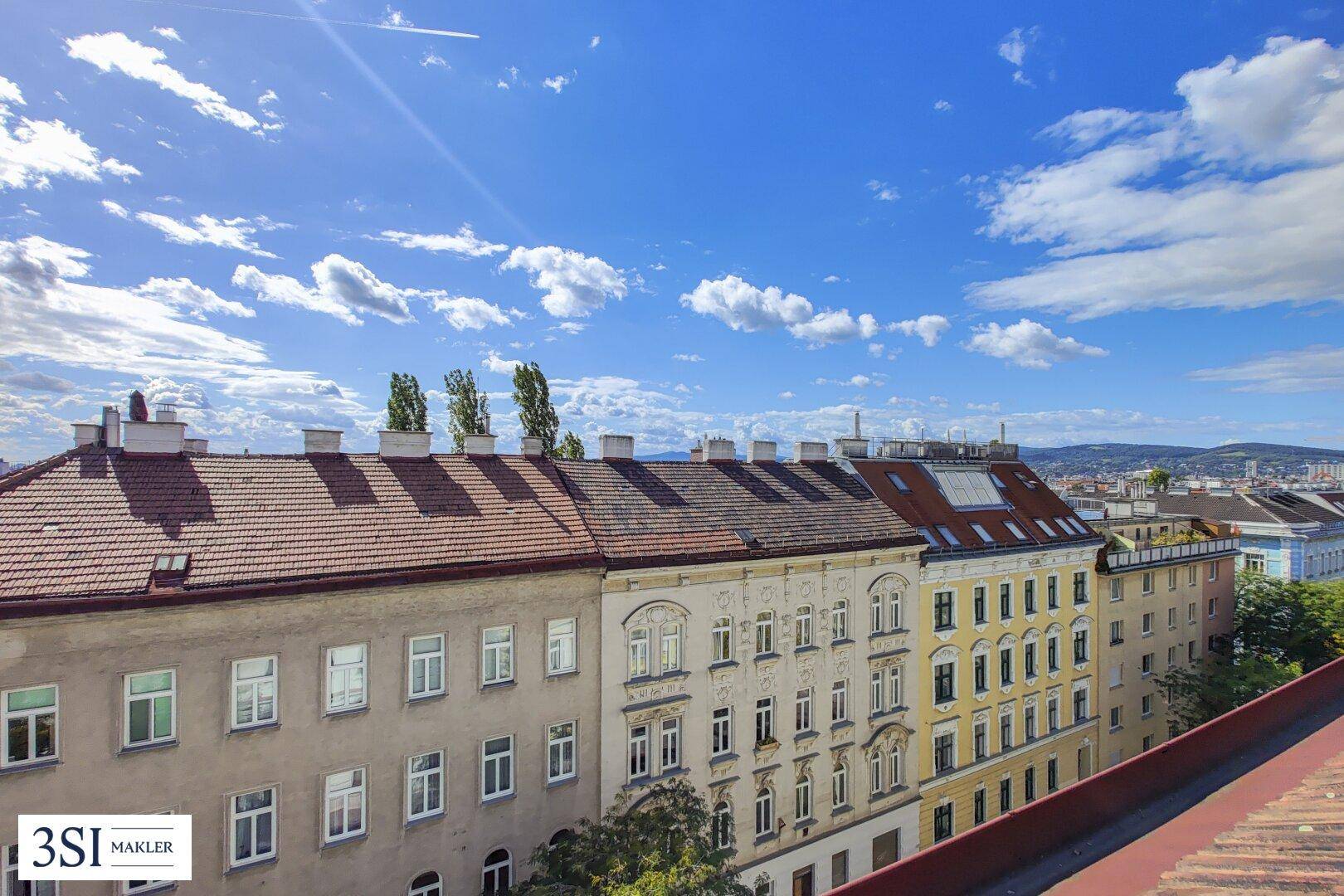 Panoramablick über die städtische Dachlandschaft unter strahlend blauem Himmel.