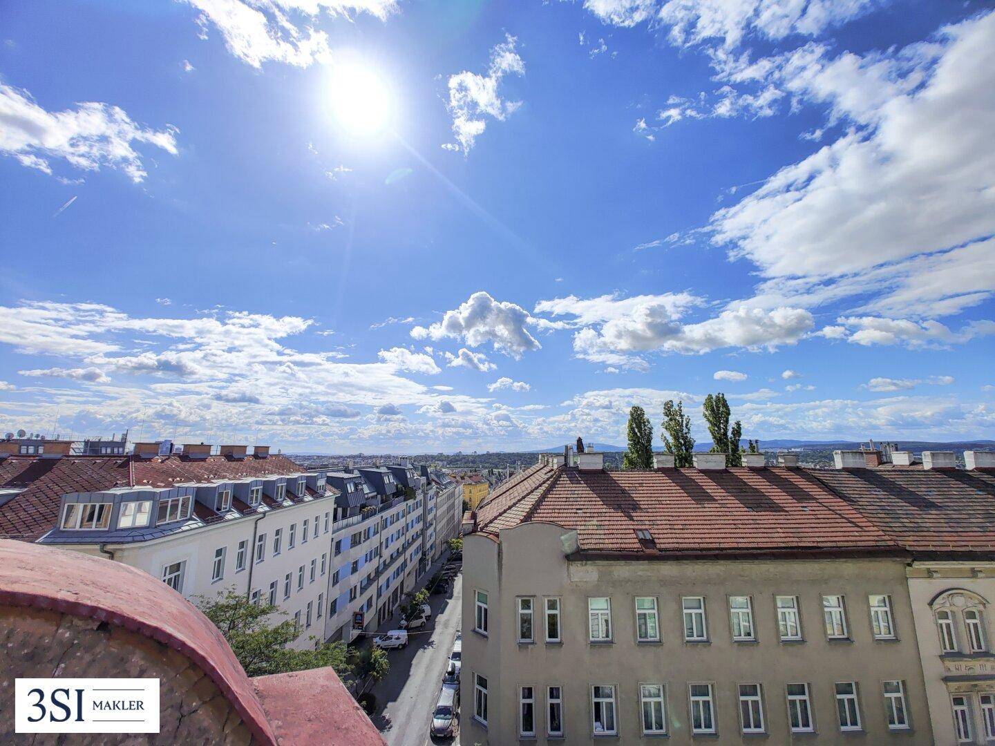 Sonniger Ausblick über die Dächer der Stadt mit weitem Horizont und blauen Himmel.