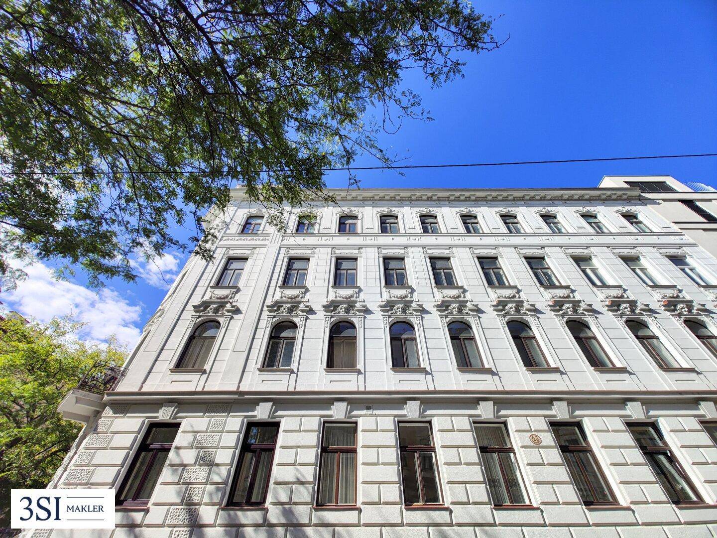 Historische Fassade eines Gebäudes mit vielen Fenstern und dekorativen Elementen.