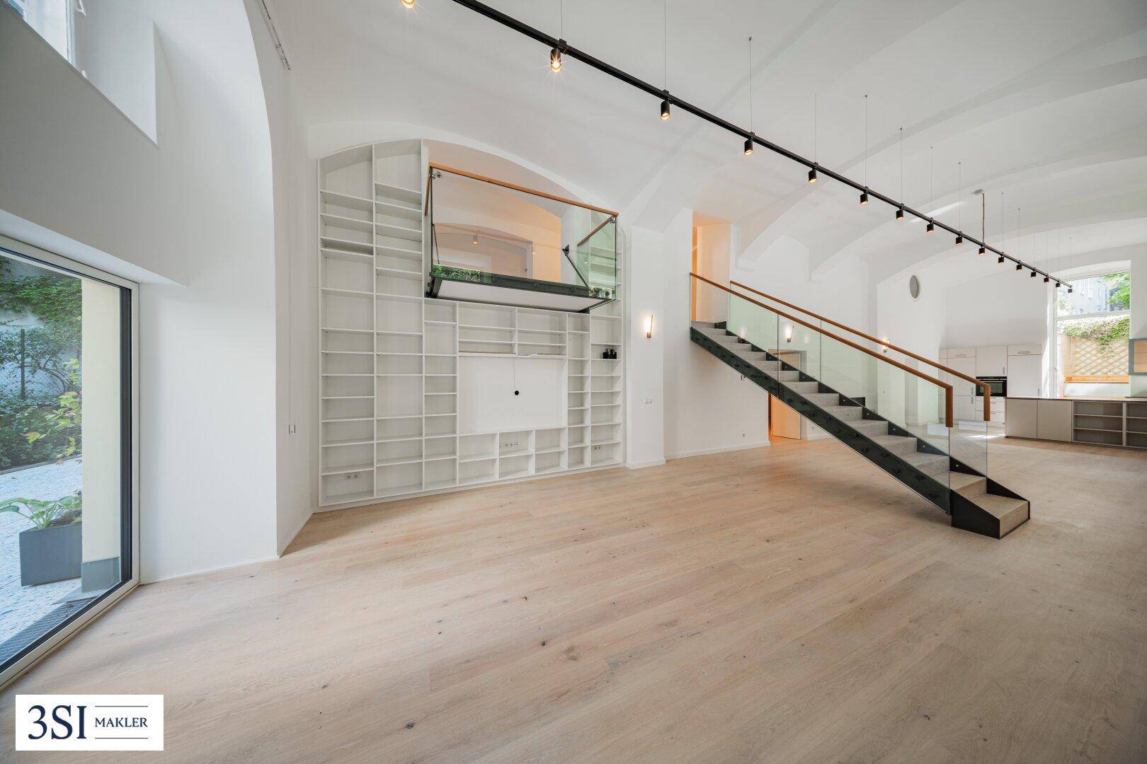 Geräumiger Wohnbereich mit hohen Gewölbedecken, Holzparkett und moderner Treppe.