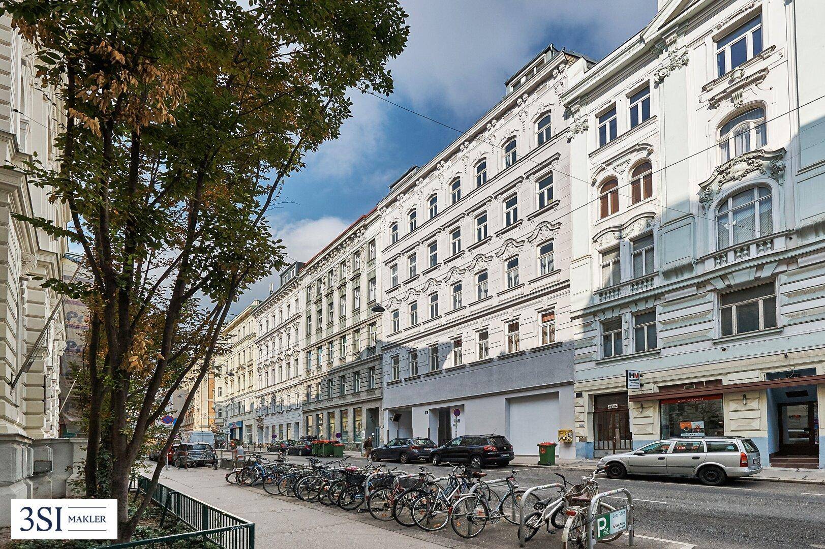 Lange Häuserzeile mit historischen Fassaden und vielen Fenstern entlang einer belebten Straße.