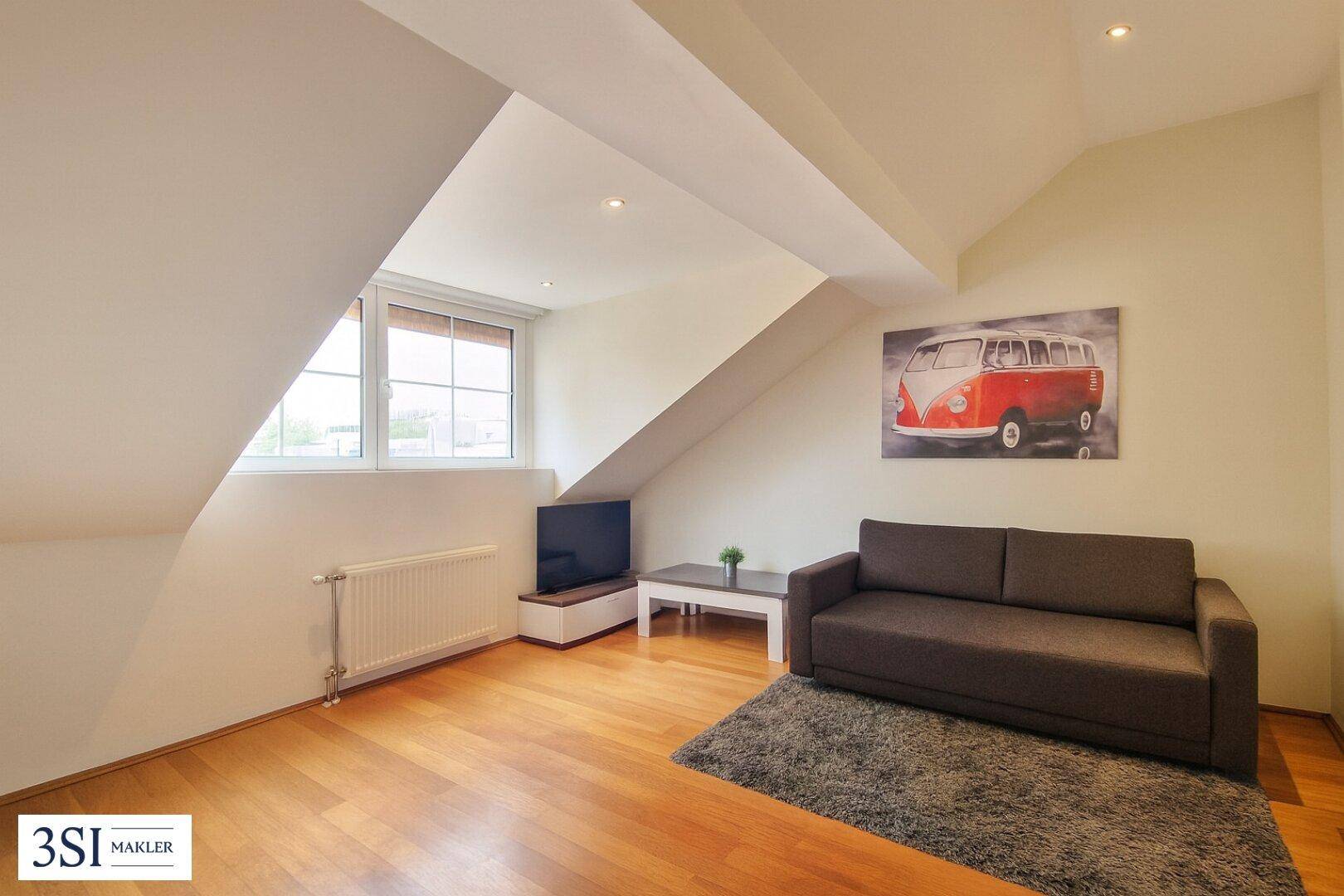 Helles Wohnzimmer im Dachgeschoss mit Holzboden und gemütlicher Couch.