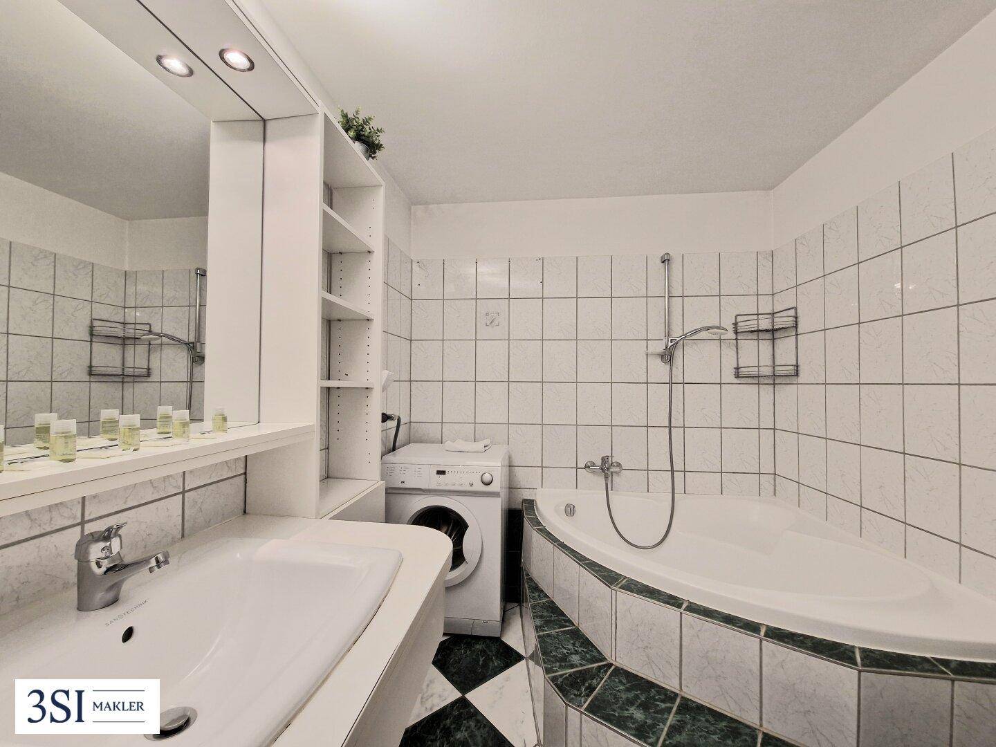 Badezimmer mit Badewanne, Waschbecken und integrierter Waschmaschine.