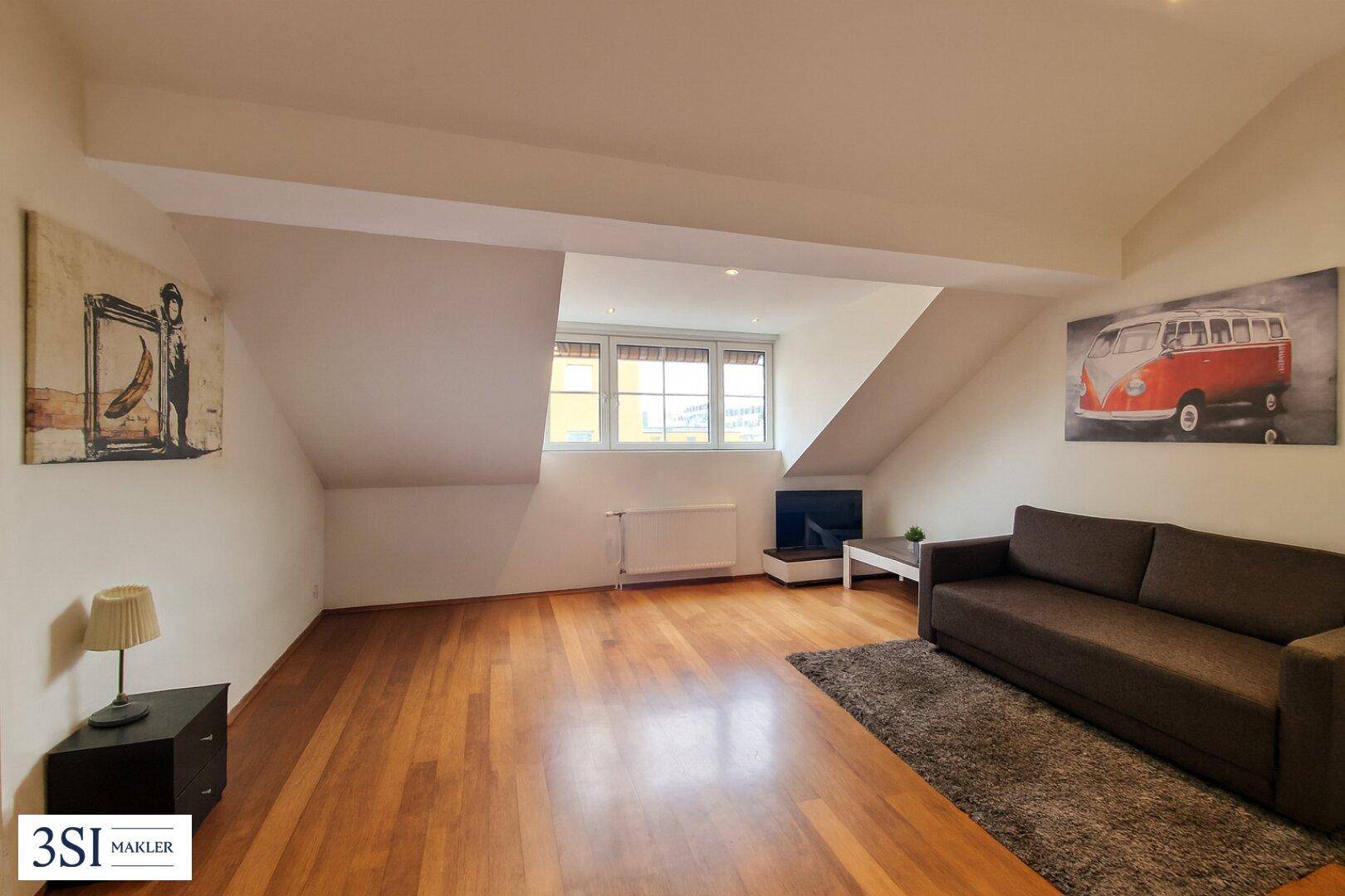 Gemütliches Wohnzimmer im Dachgeschoss mit Holzboden und schrägen Wänden.