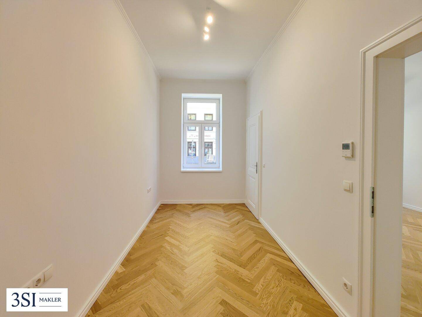 Kleineres, helles Zimmer mit Fischgrätparkett und einem Fenster, geeignet als Schlaf- oder Arbeitszimmer.