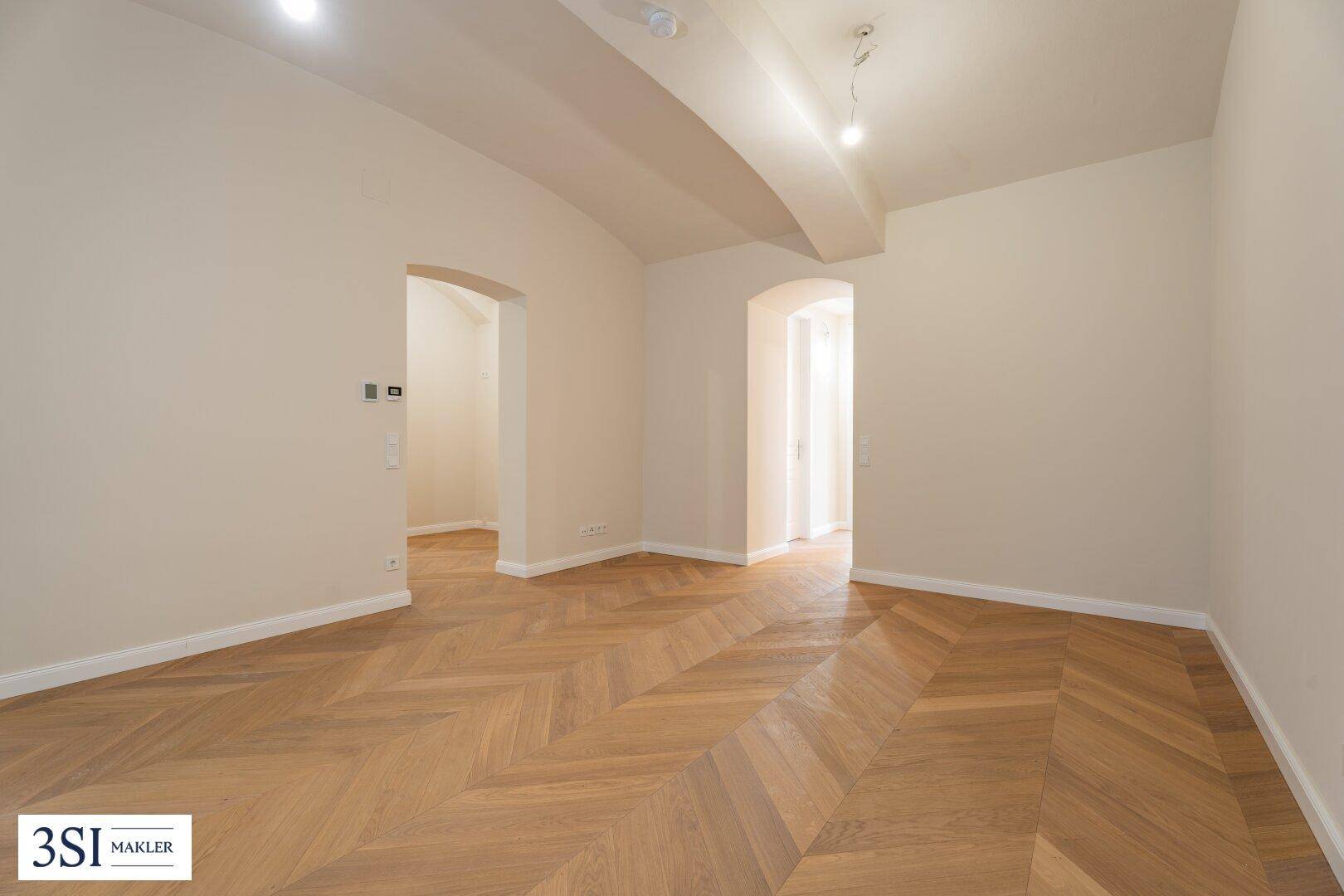 Geräumiger Innenraum mit stilvollem Fischgrätparkett und architektonischen Deckendetails.