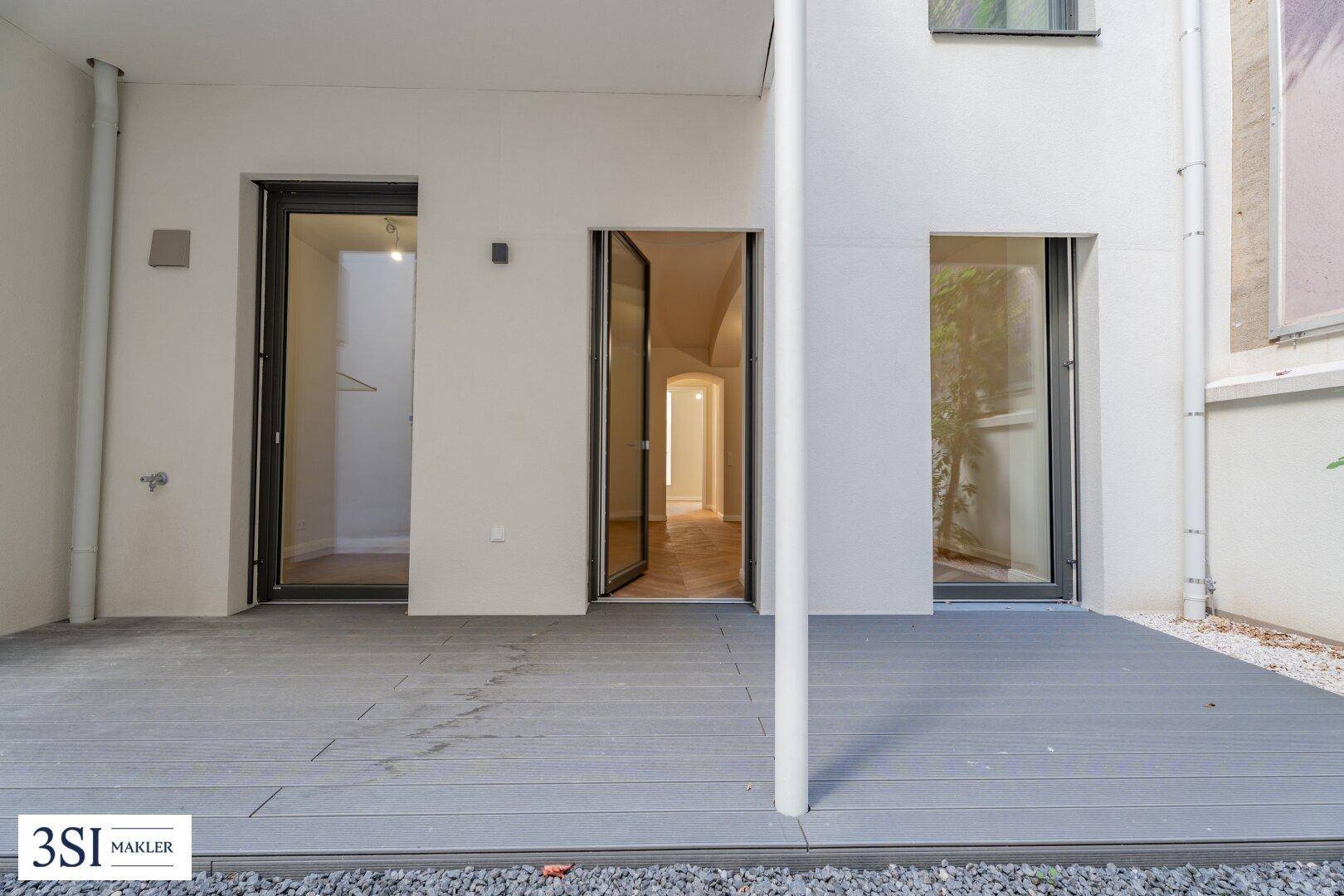 Geräumige Terrasse mit modernen grauen Dielen und direktem Zugang zu den Innenräumen.