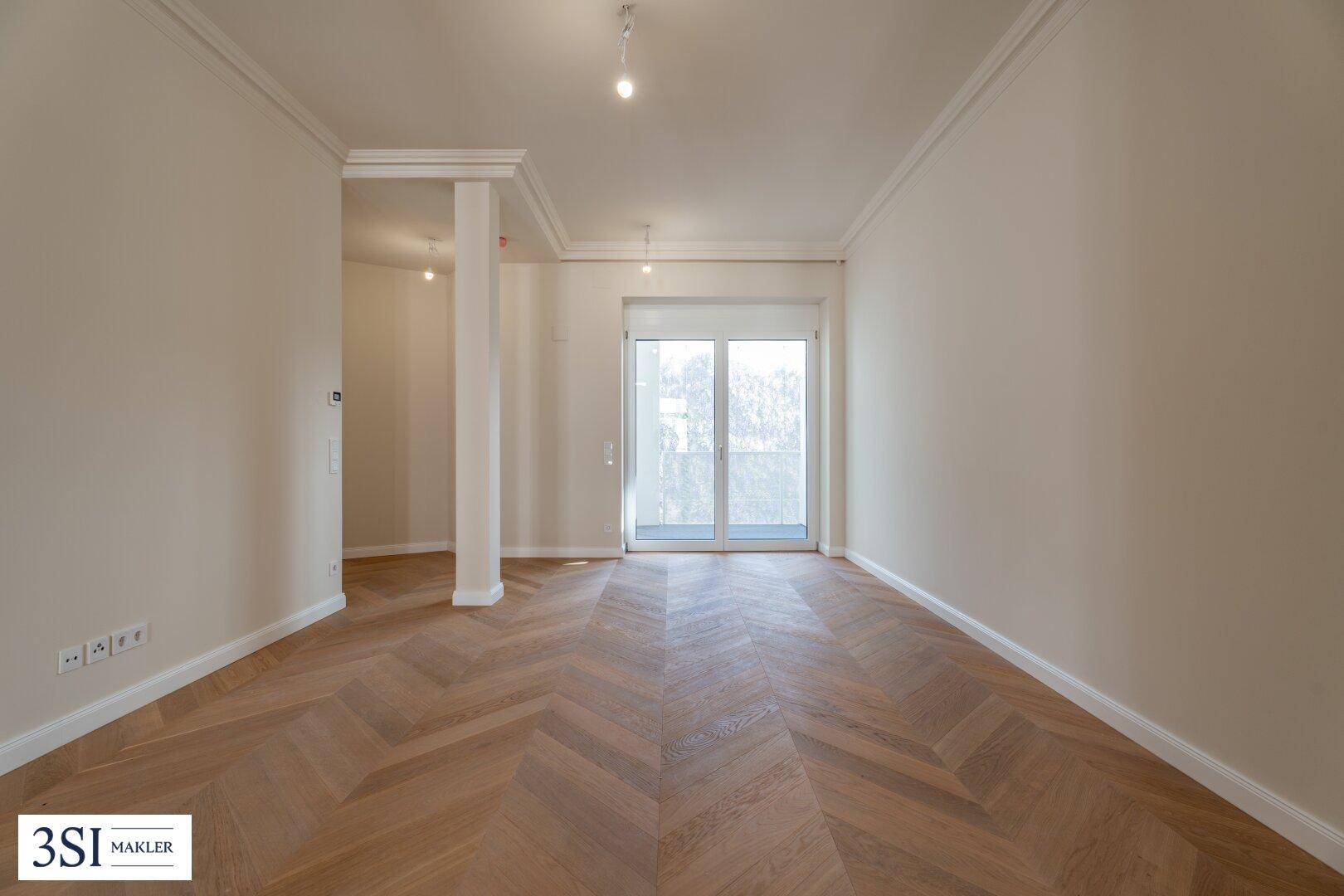 Heller Raum mit Fischgrätparkett und Zugang zu einem Balkon, ideal für ein Wohn- oder Schlafzimmer.