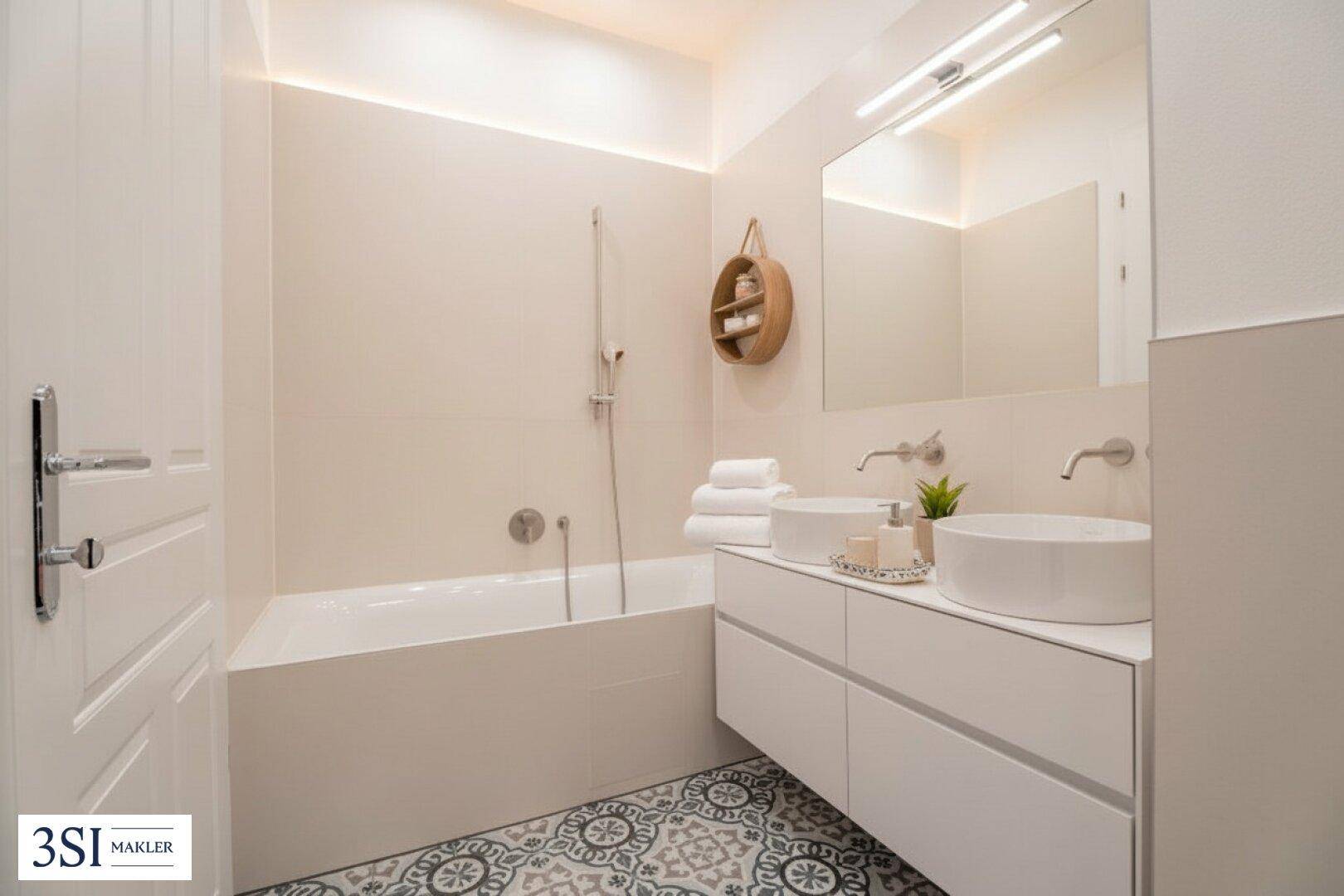 Modernes Badezimmer mit Doppelwaschbecken, Badewanne und gemusterten Bodenfliesen.
