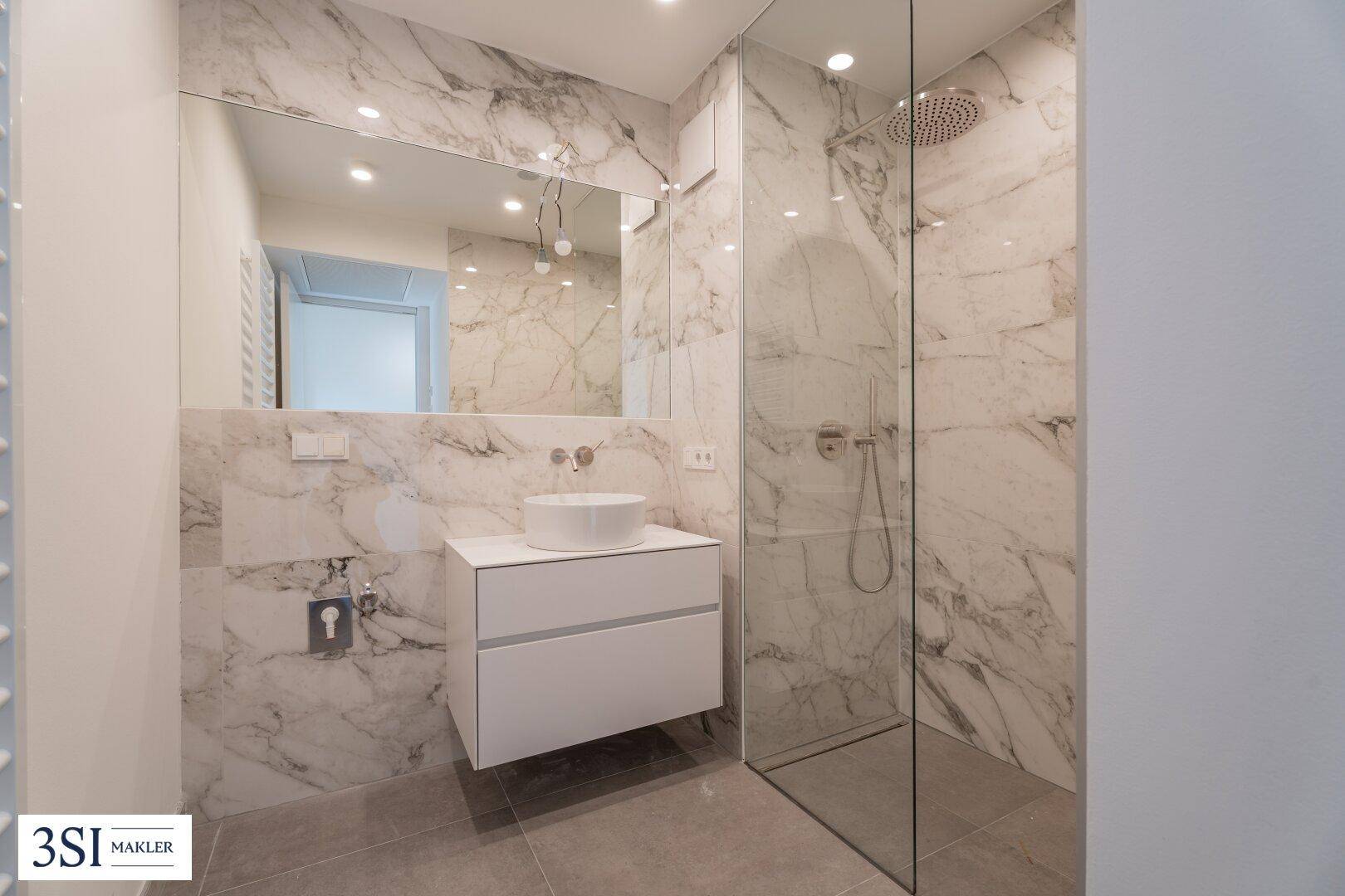 Modernes Badezimmer mit Marmorfliesen, Einzelwaschbecken und einer geräumigen begehbaren Dusche.