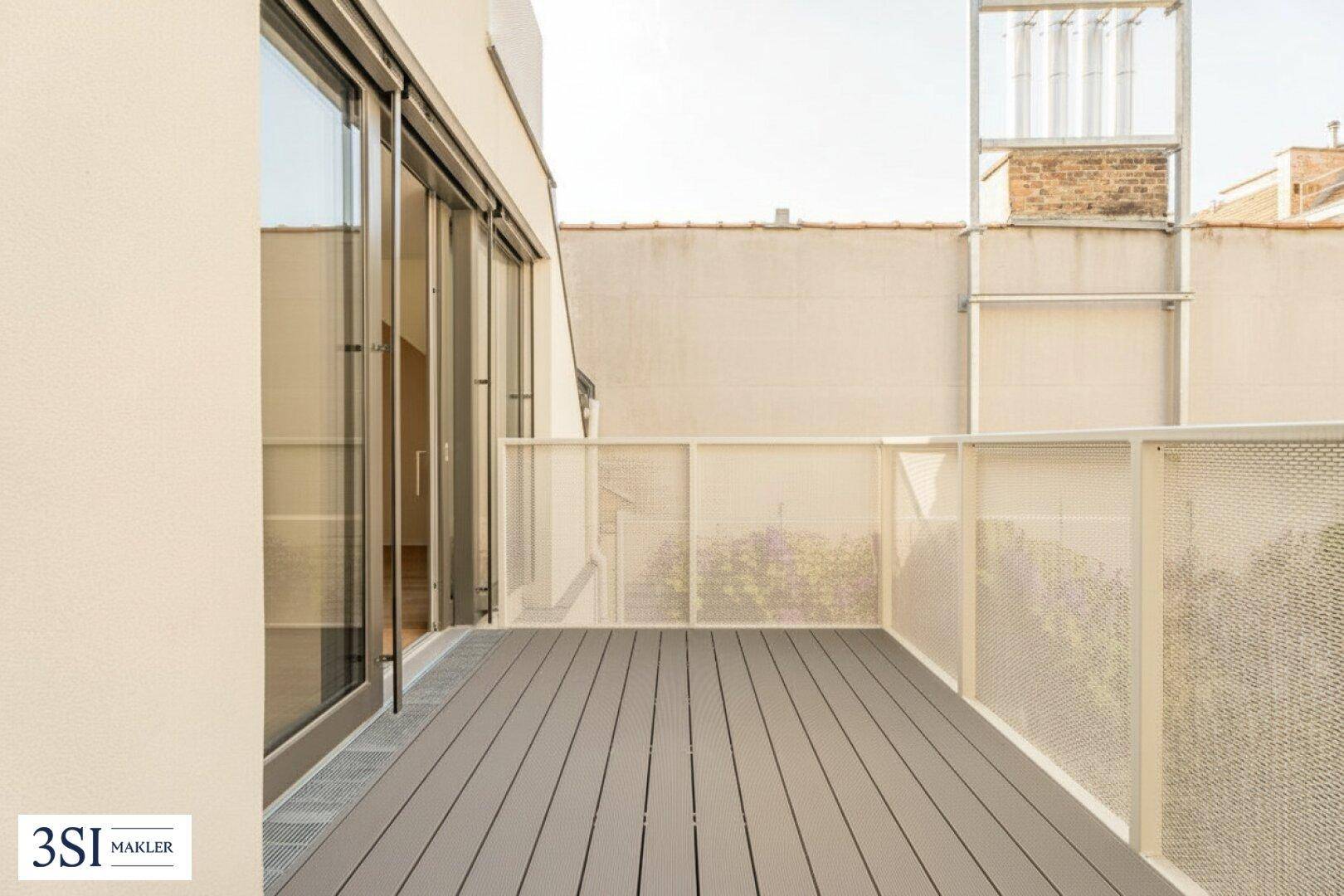 Moderner Balkon mit Holzdielenboden und Blick auf die umliegenden Gebäude.