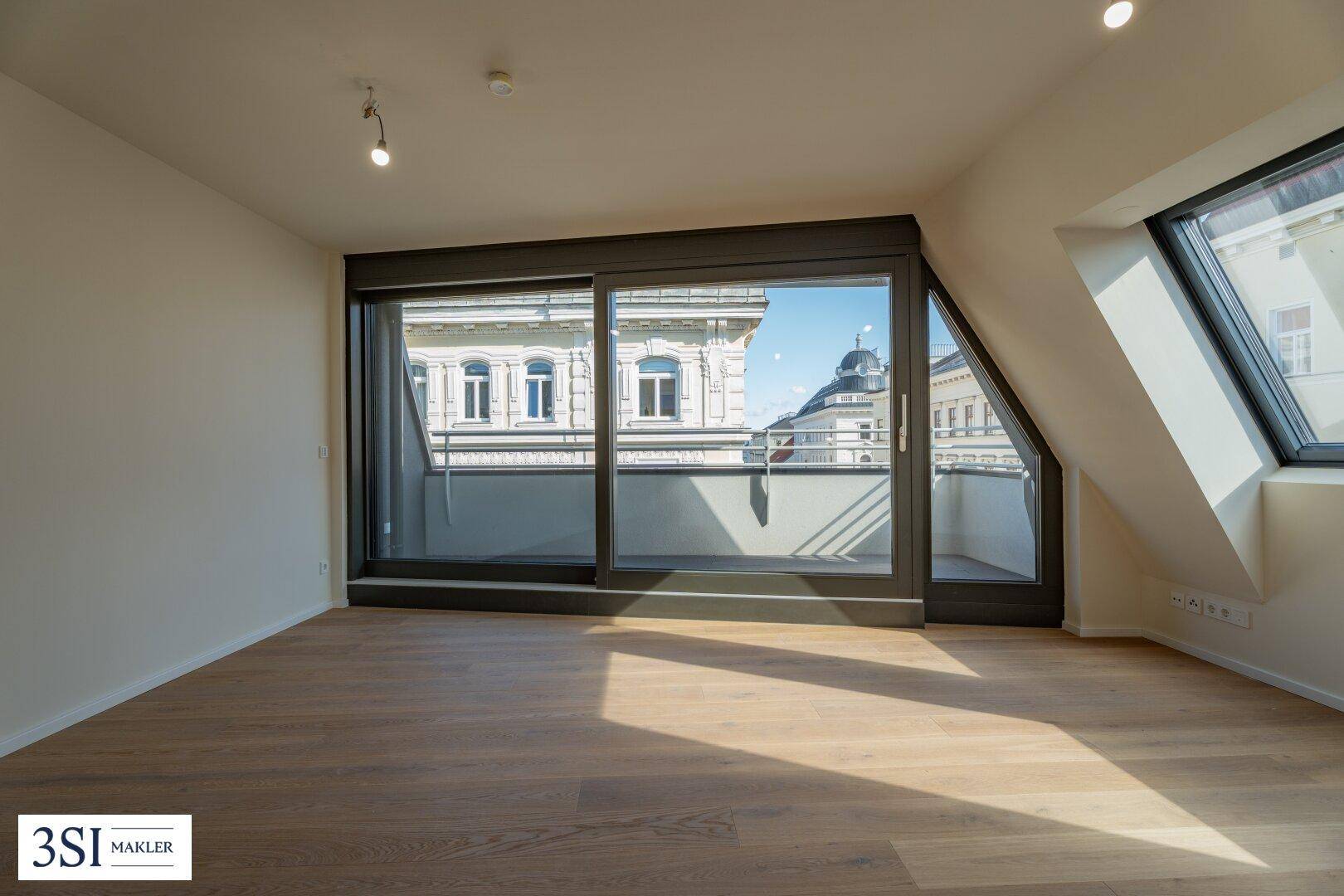Lichtdurchfluteter Wohnbereich im Dachgeschoss mit Holzboden und direktem Balkonzugang.