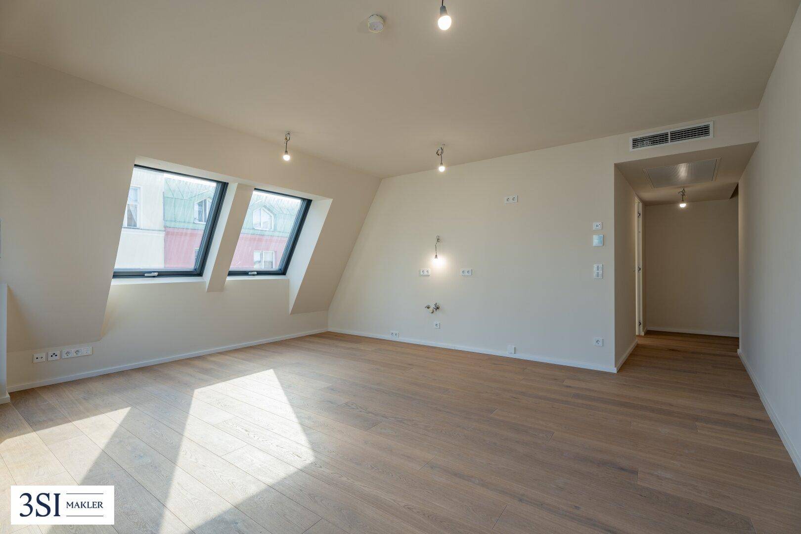 Geräumiges Dachgeschosszimmer mit Holzboden, Dachfenstern und moderner Belüftung.