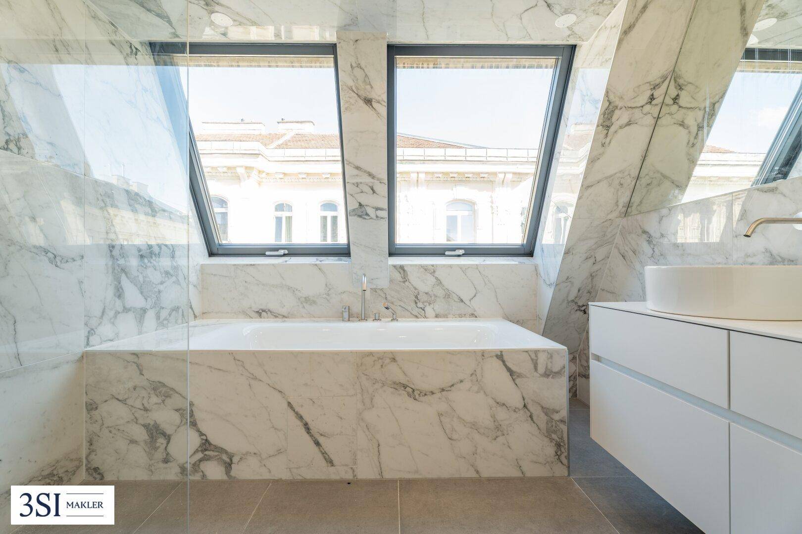Luxuriöses Badezimmer mit integrierter Badewanne und Marmorverkleidung, unter großen Dachfenstern mit Stadtblick.