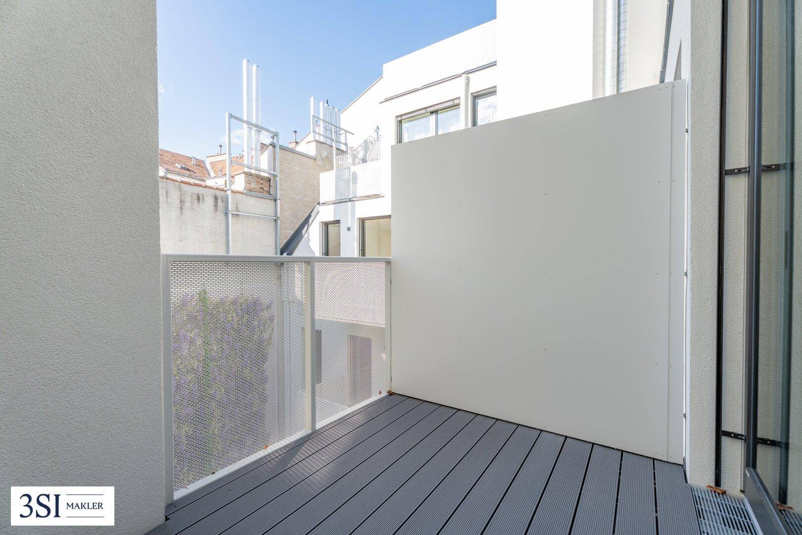 Moderner Balkon mit Holzdielenboden und perforierter Metallbrüstung, bietet einen privaten Außenbereich im Neubau.