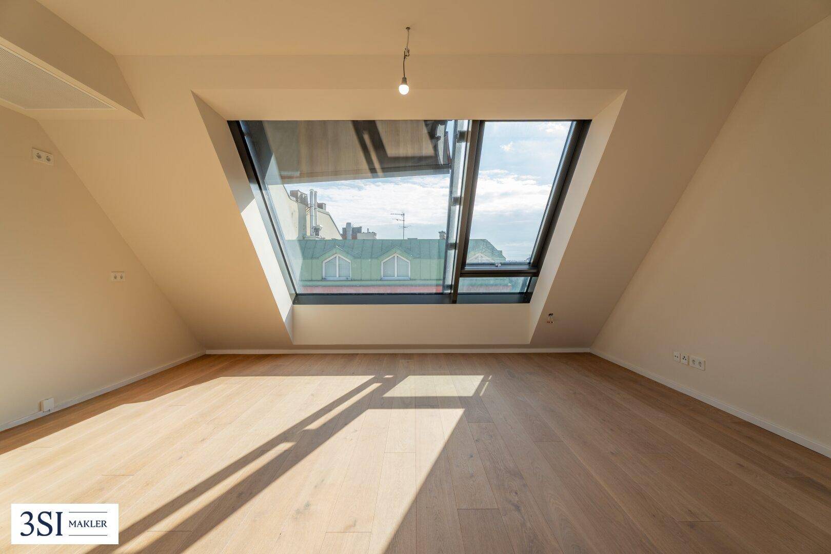 Geräumiger Dachgeschossraum mit hellem Holzboden und einer beeindruckenden Fensterfront für optimale Belichtung.